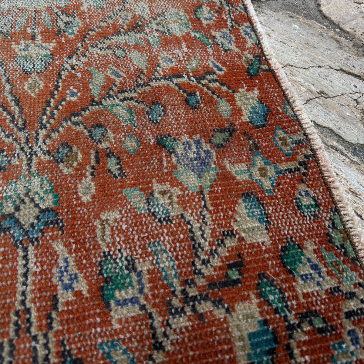 Close-up of the red Turkish distressed floral runner rug showing floral details, hand-knotted weave, wool and cotton and low pile.