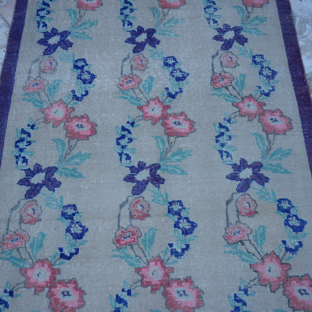 Close-up of the beige Turkish floral vintage rug showing floral details, hand-knotted weave, wool and cotton and low pile.