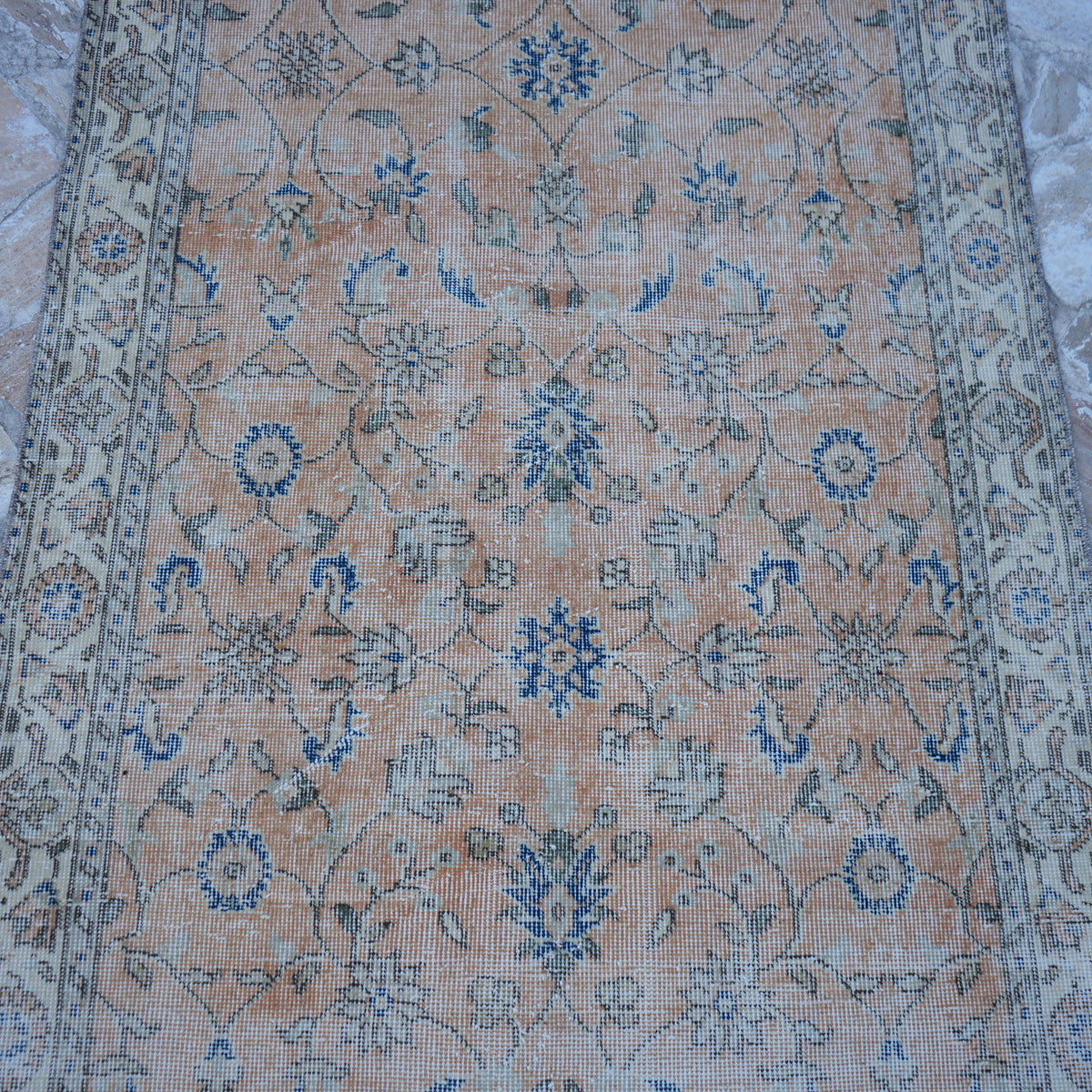 Close-up of the orange Turkish floral vintage rug showing floral details, hand-knotted weave, wool and cotton and low pile.