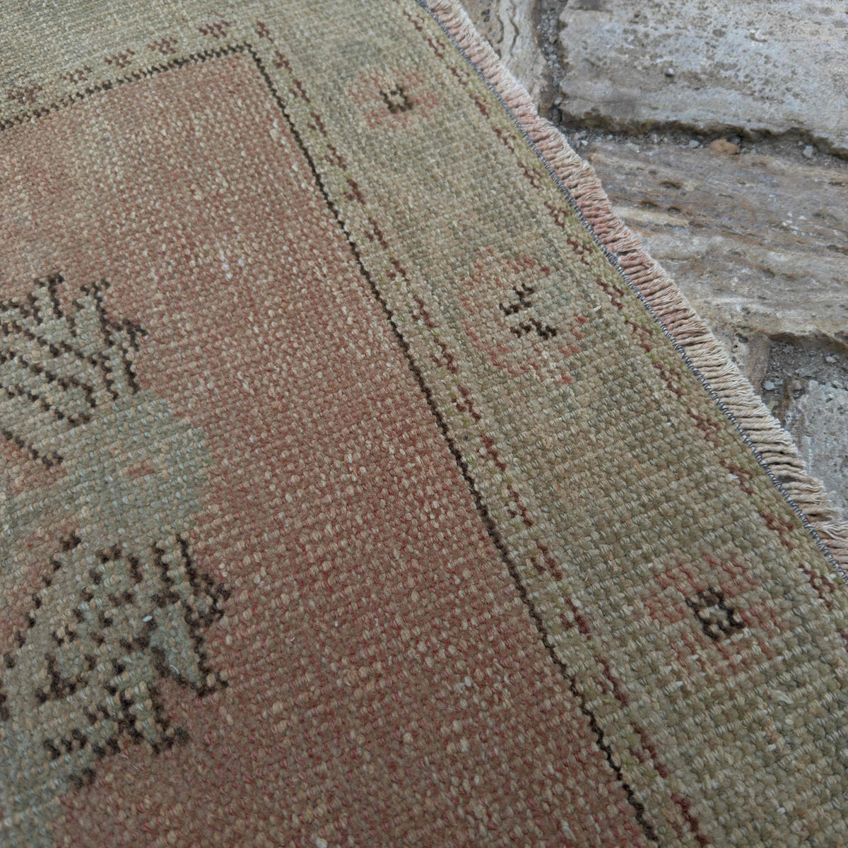 Close-up of the pale red Turkish geometric runner rug showing medallion details, hand-knotted weave, wool and cotton and low pile.