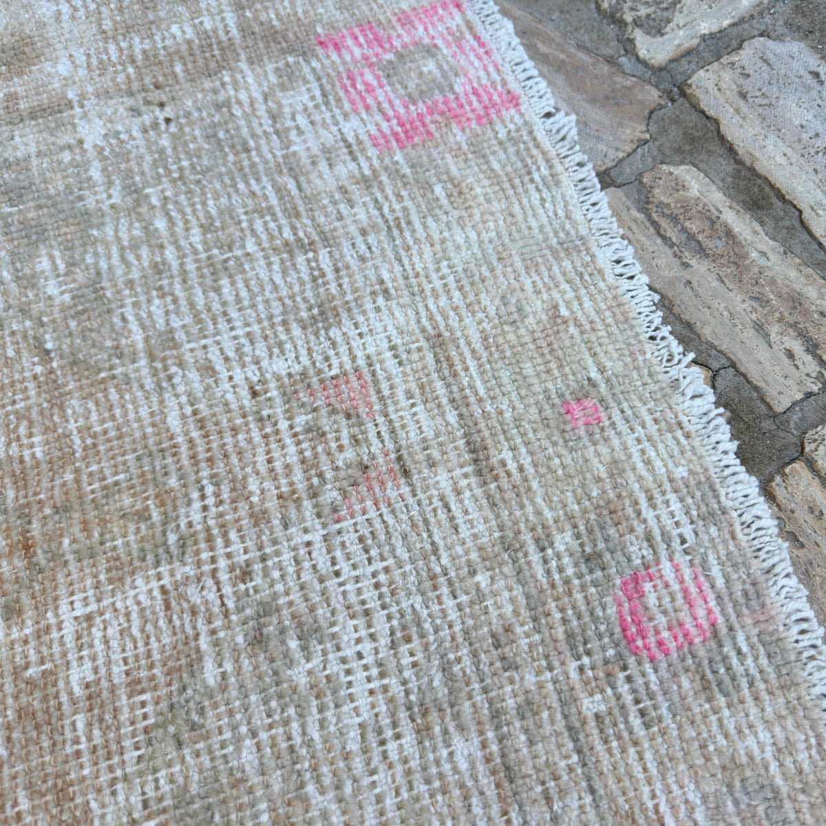 Close-up of the beige Turkish hand-knotted rug showing neutral details, hand-knotted weave, wool and cotton and low pile.