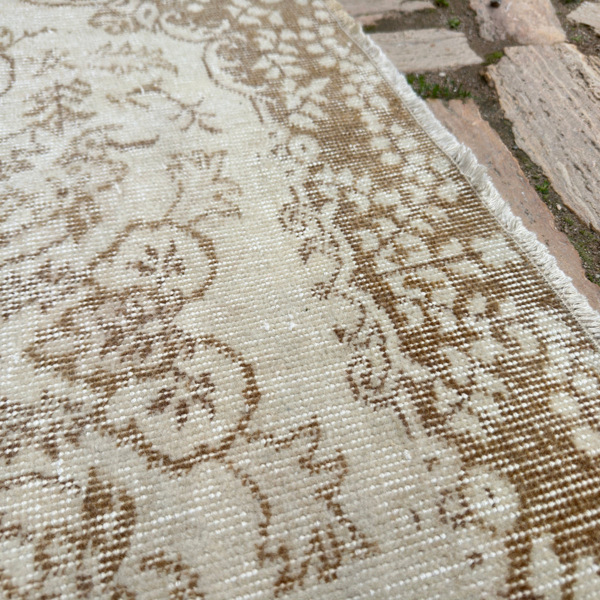 Close-up of the beige Turkish handknotted rug showing medallion details, hand-knotted weave, wool and cotton and low pile.