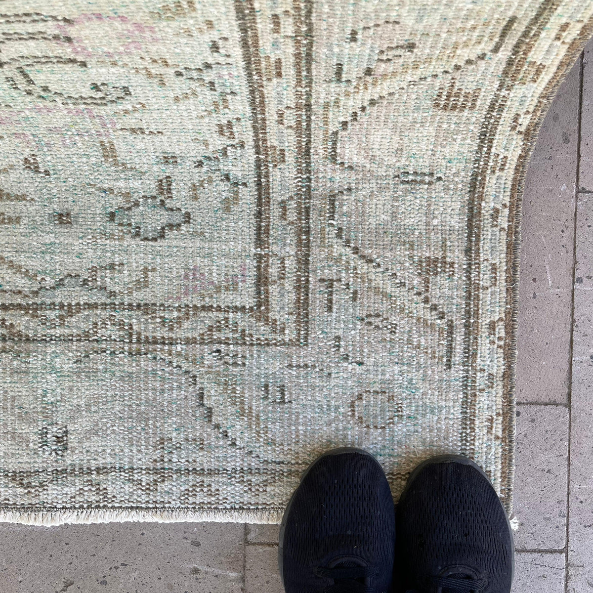 Close-up of the pale green Turkish handknotted rug showing medallion details, hand-knotted weave, wool and cotton and low pile.