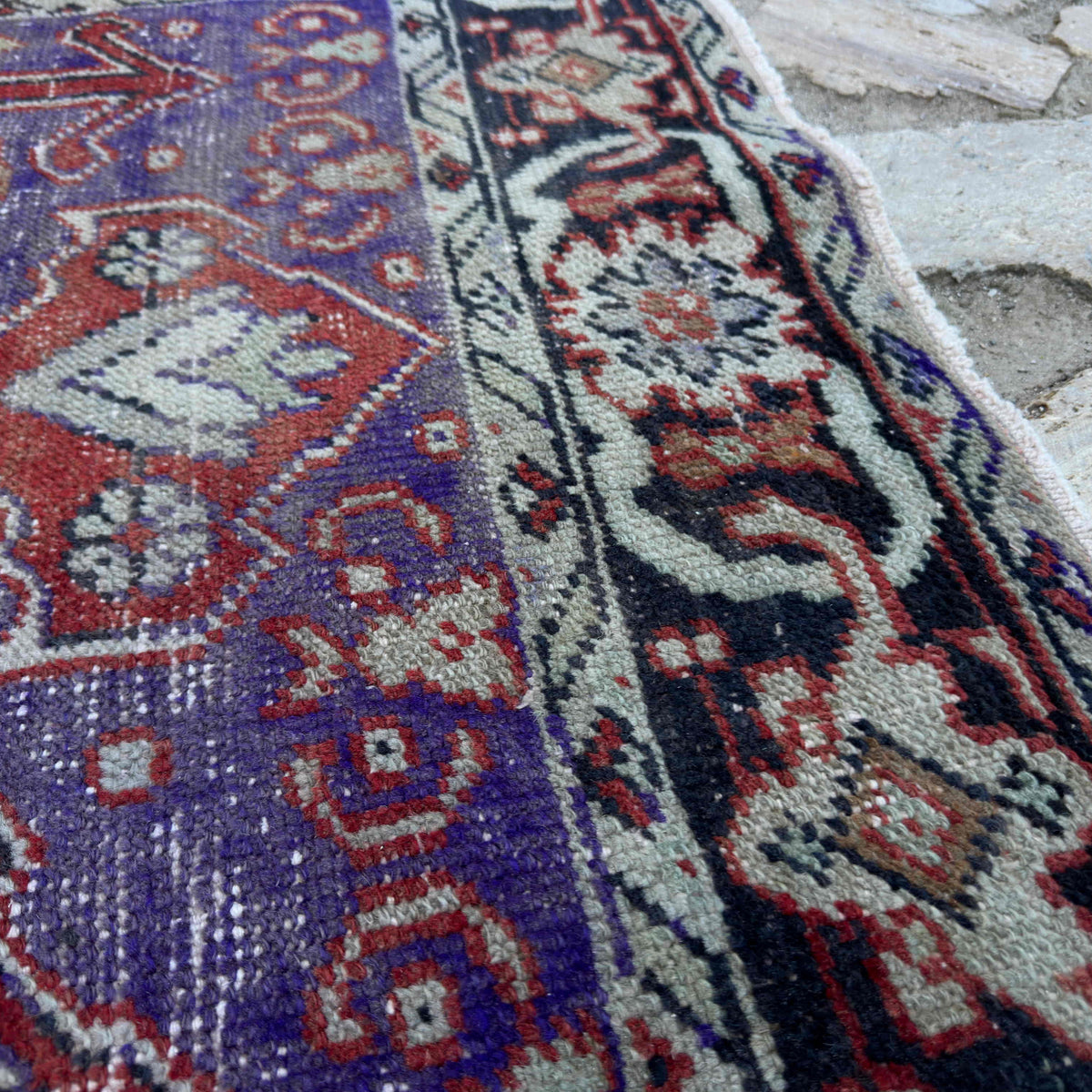Close-up of the purple Turkish handknotted rug showing geometric details, hand-knotted weave, wool and cotton and low pile.