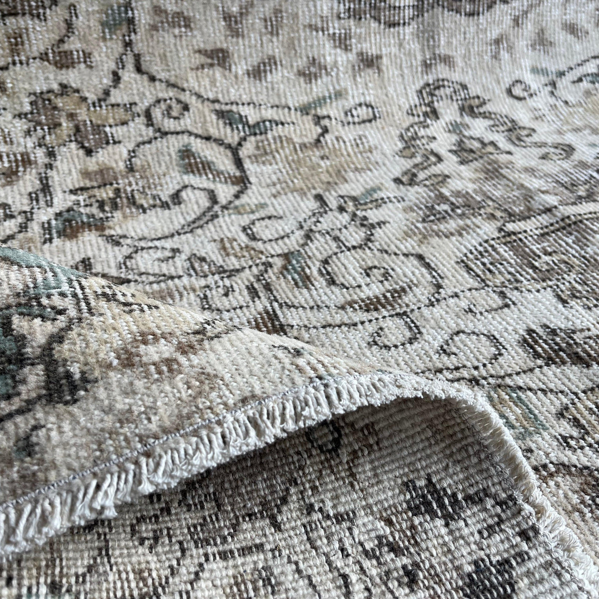Close-up of the green Turkish handknotted rug showing neutral details, hand-knotted weave, wool and cotton and low pile.