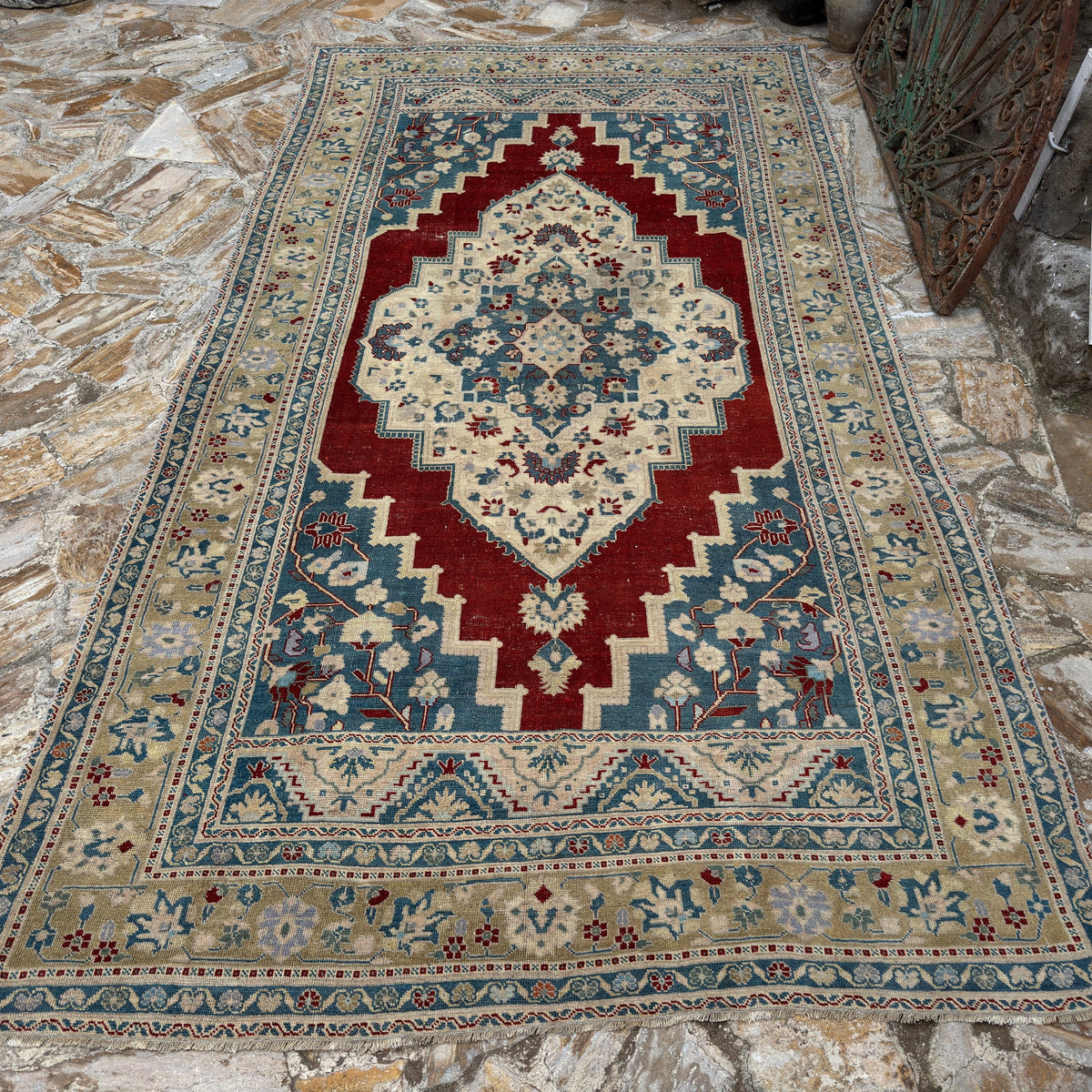 Red 6' x 11' Turkish handmade traditinoal rug in wool, shown on the floor.