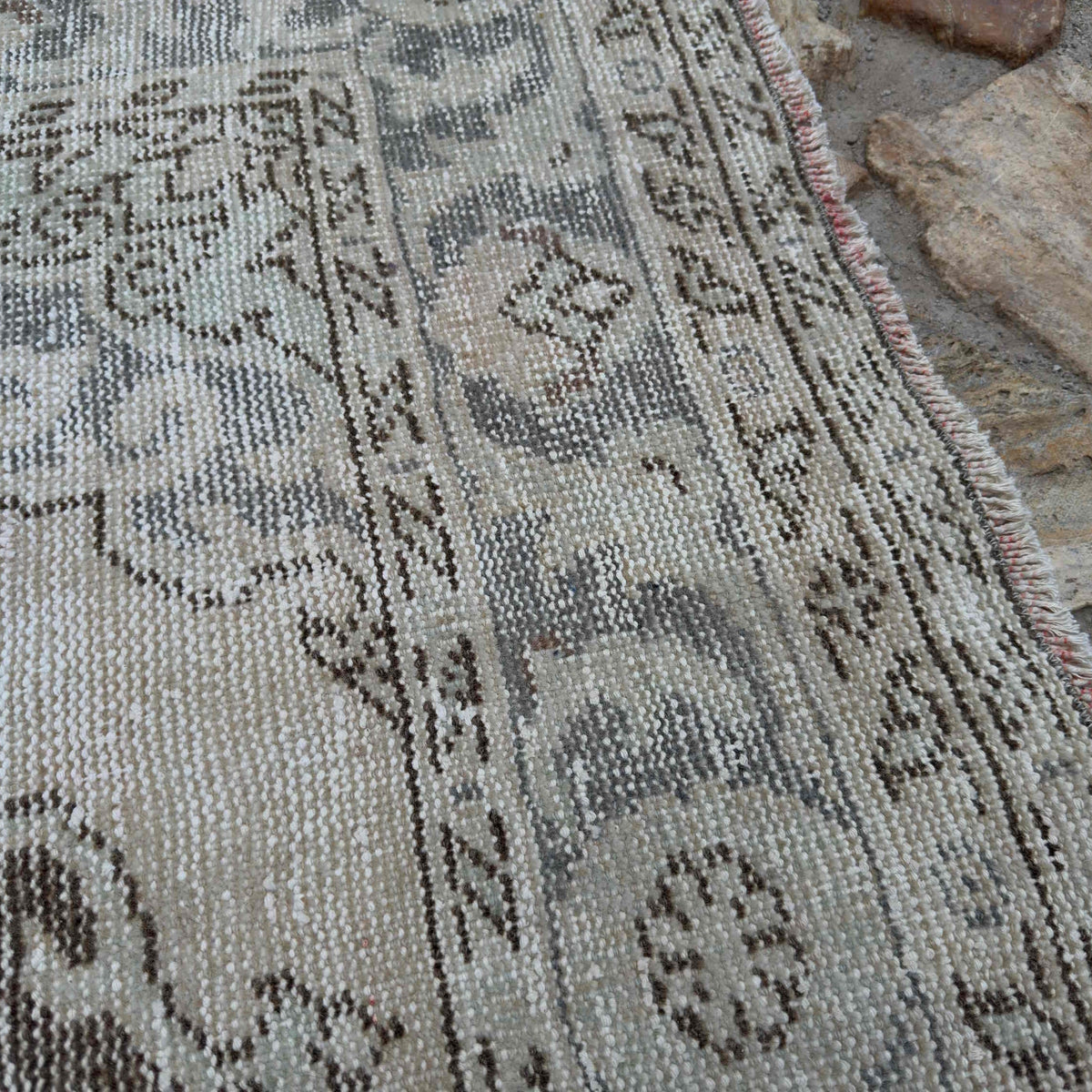Close-up of the pale blue Turkish large traditional rug showing neutral details, hand-knotted weave, wool and cotton and low pile.
