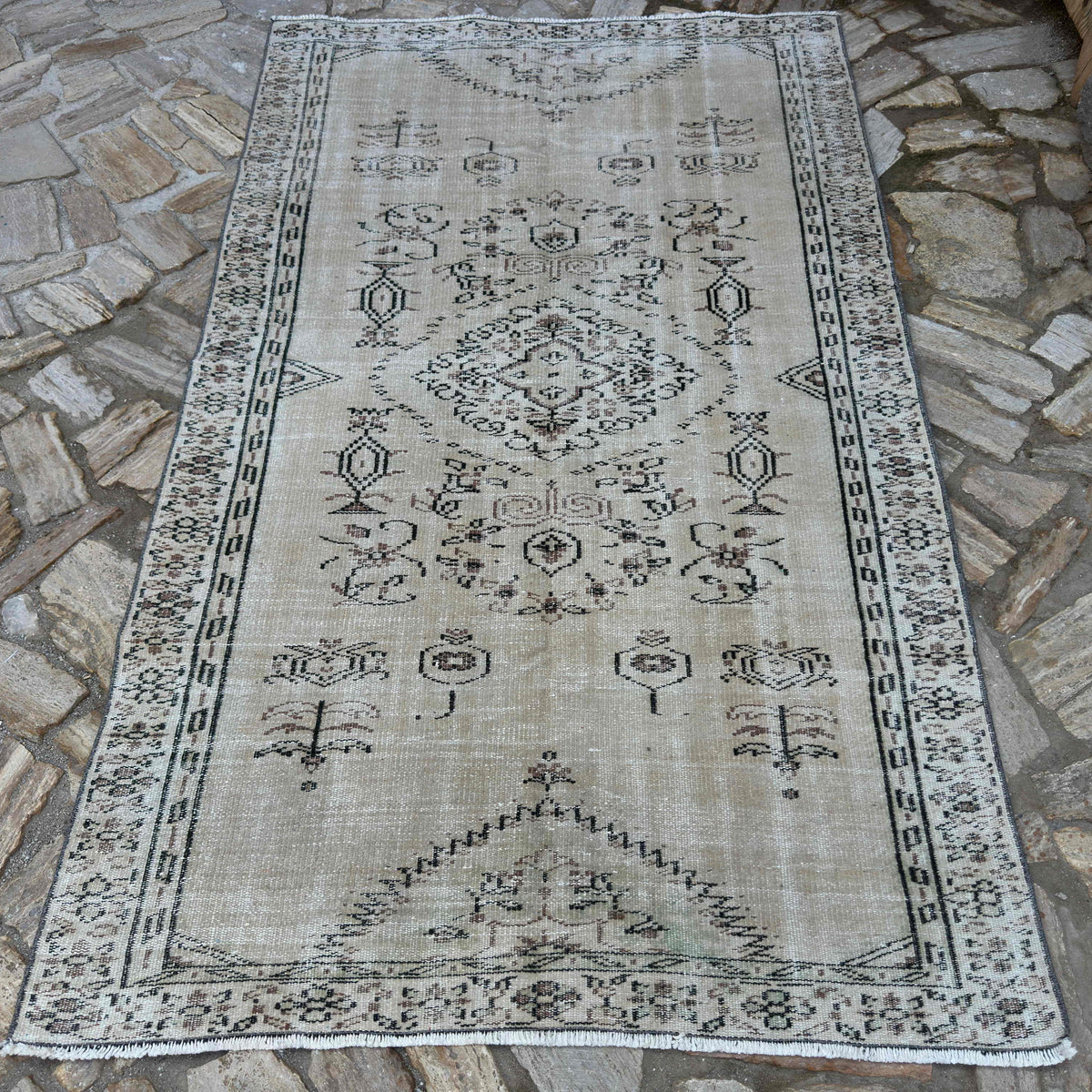 Beige 5' x 8' Turkish large vintage rug in wool and cotton, shown on the floor.