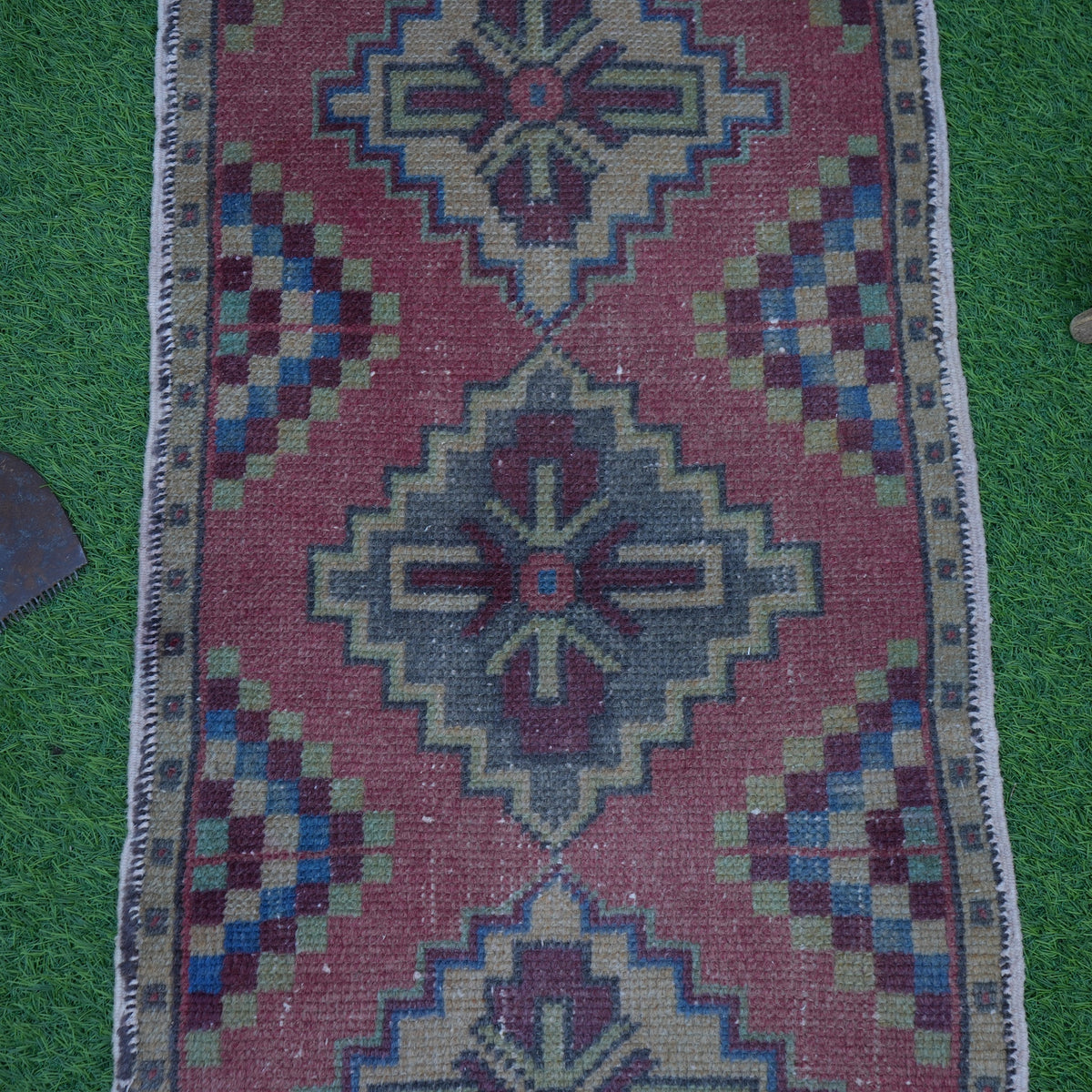 Close-up of the red mini turkish rug showing geometric details, hand-knotted weave, wool and cotton and low pile.