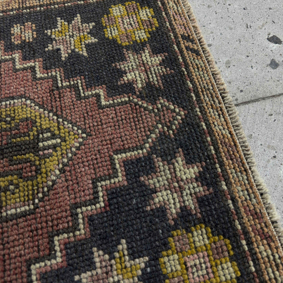 Close-up of the red mini turkish rug showing traditional details, hand-knotted weave, wool and cotton and low pile.