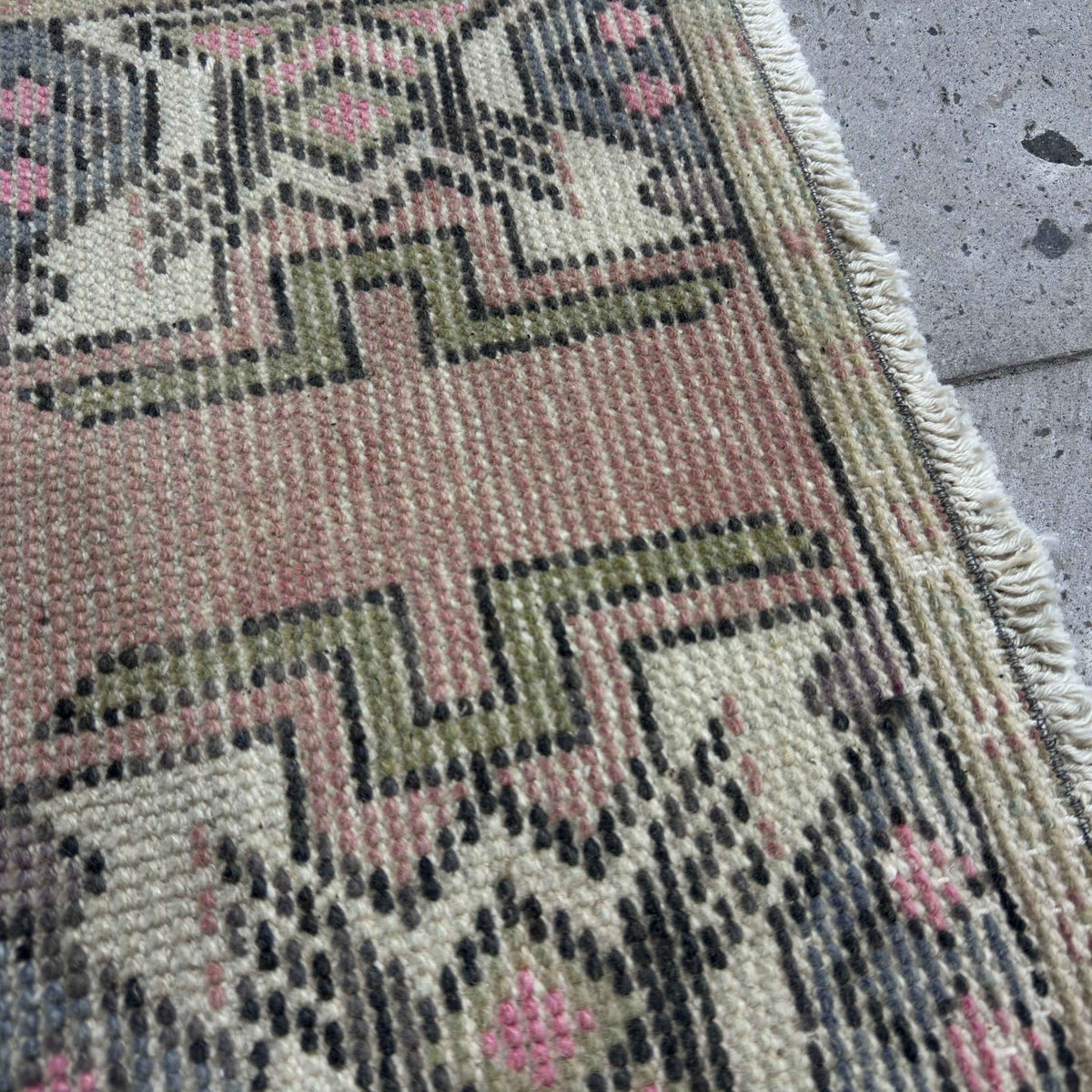 Close-up of the pink Turkish mini vintage rug showing traditional details, hand-knotted weave, wool and cotton and low pile.