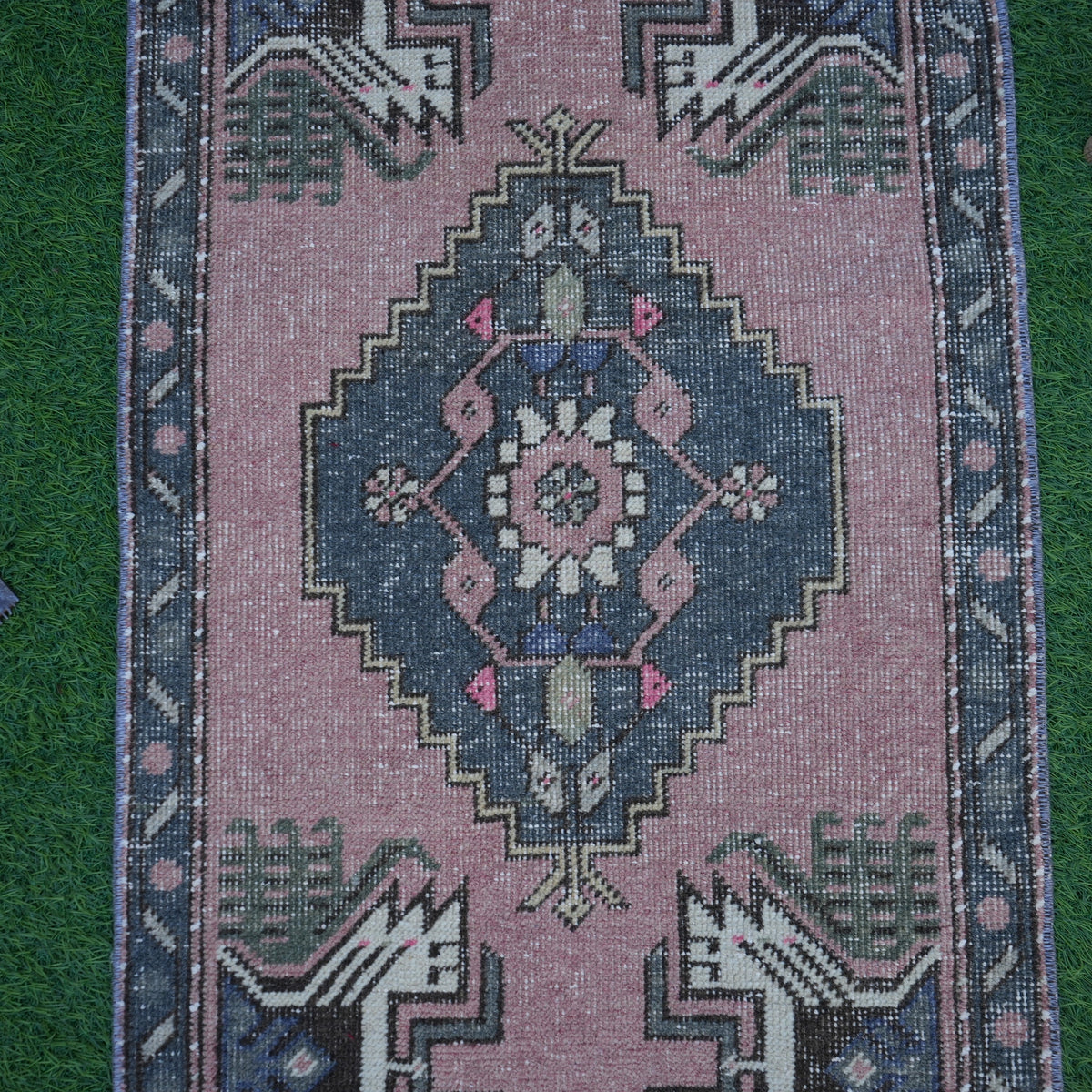 Close-up of the pink Turkish mini vintage rug showing traditional details, hand-knotted weave, wool and cotton and low pile.