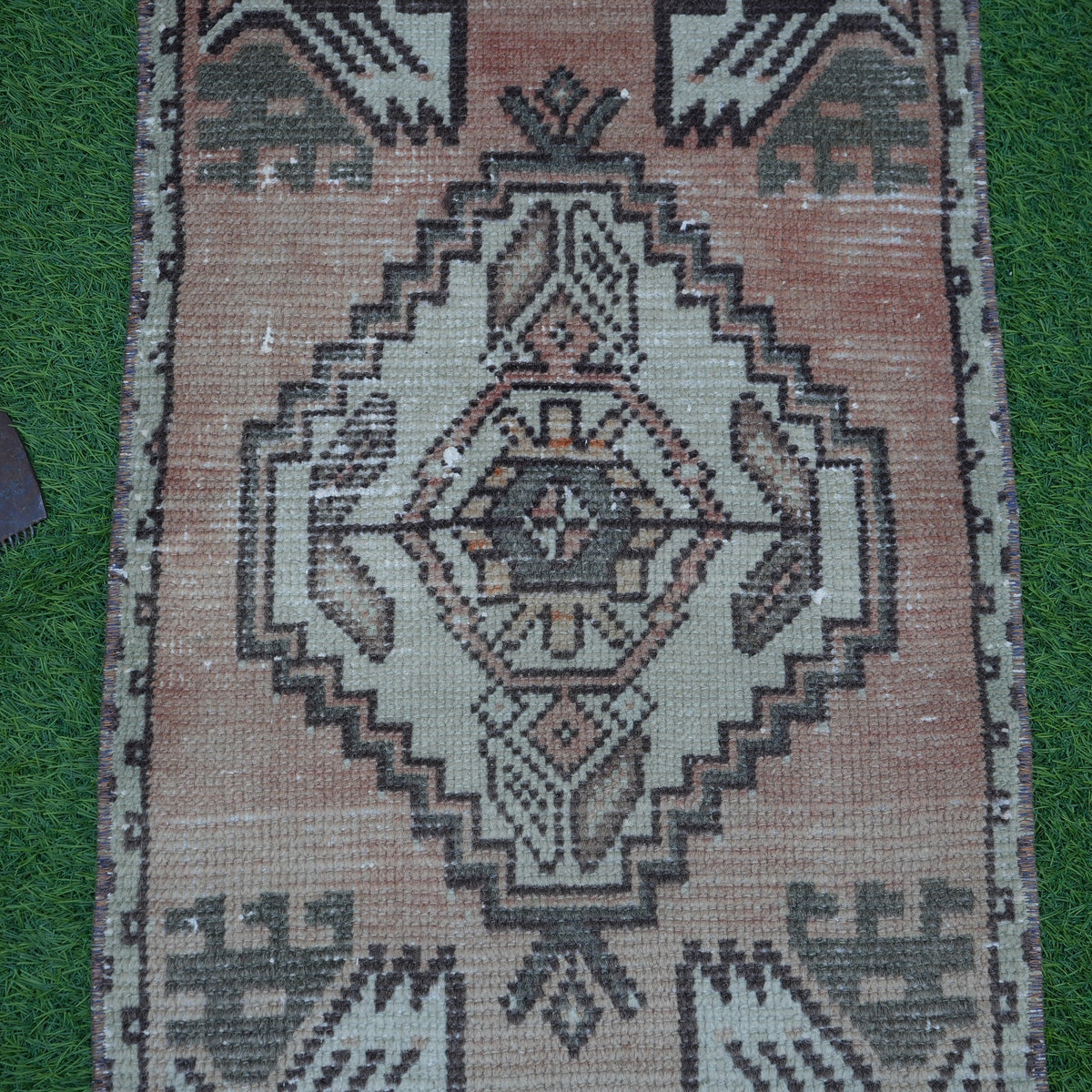 Close-up of the orange Turkish small vintage carpet showing traditional details, hand-knotted weave, wool and cotton and low pile.
