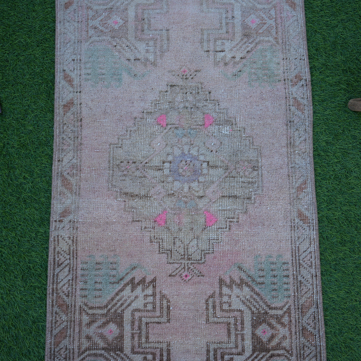 Close-up of the pink Turkish small vintage rug showing traditional details, hand-knotted weave, wool and cotton and low pile.
