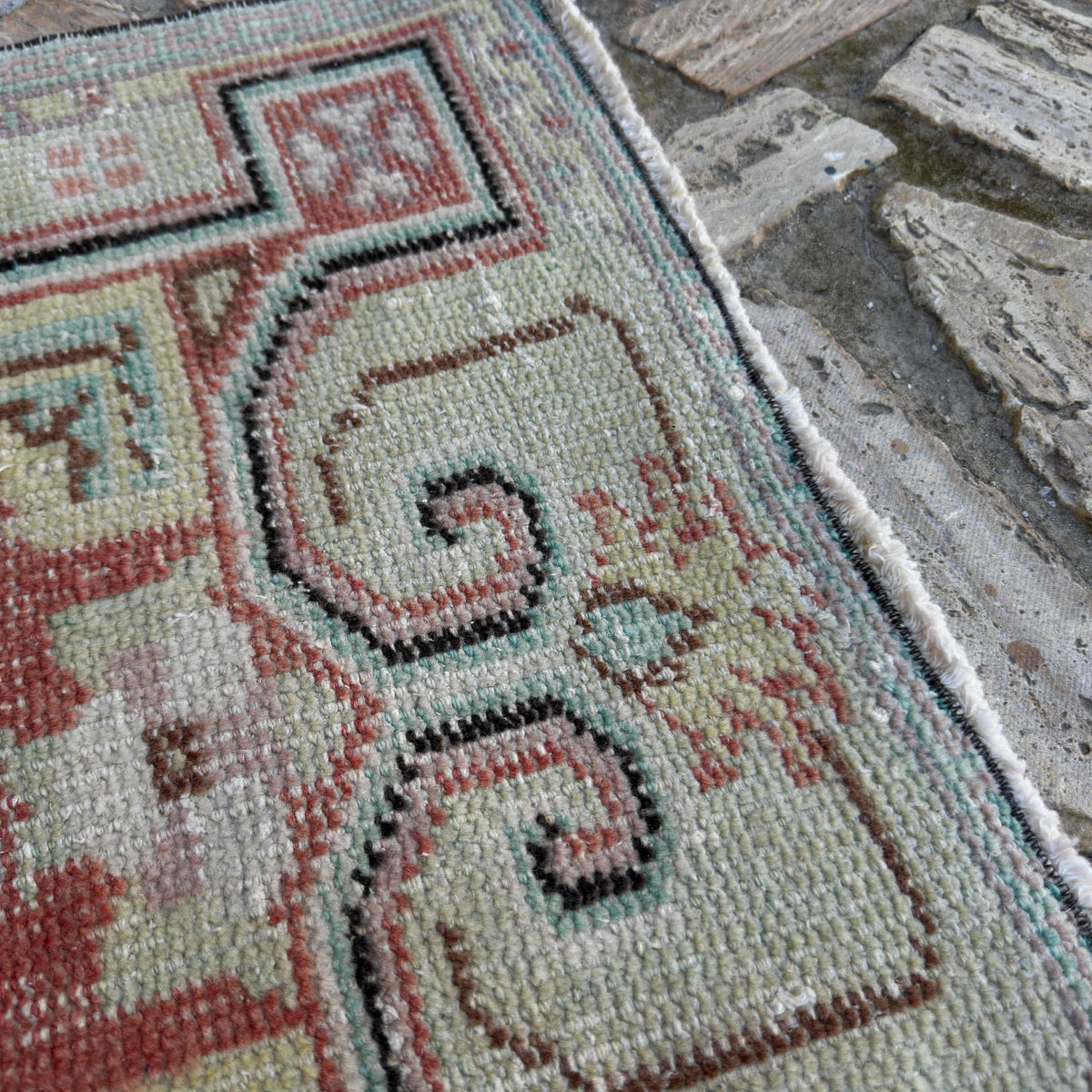 Close-up of the red turkish rug showing traditional details, hand-knotted weave, wool and cotton and low pile.