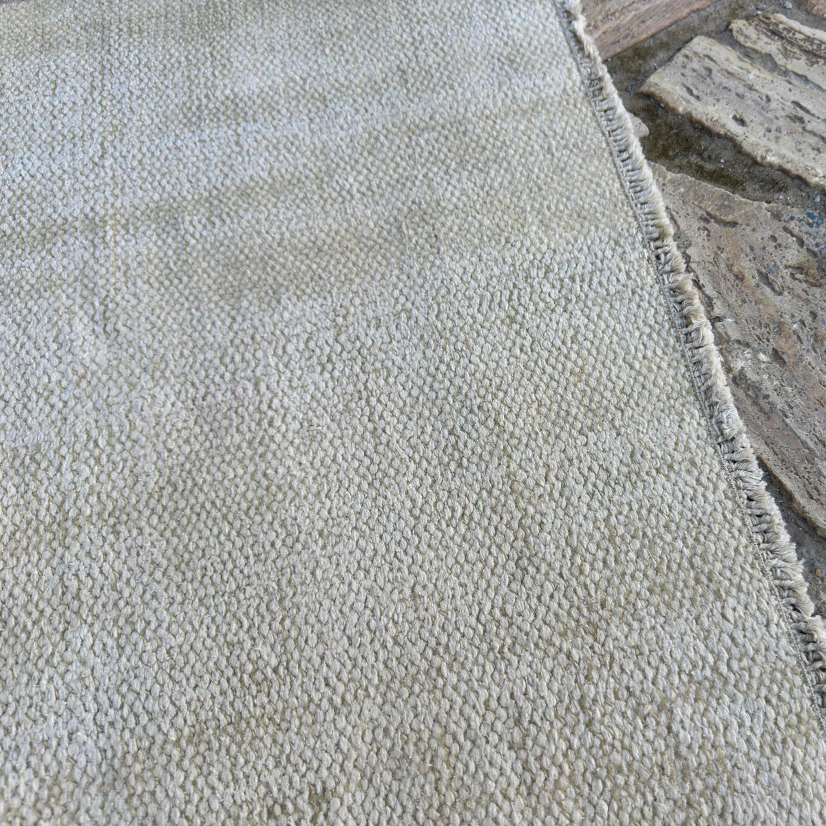 Close-up of the beige turkish rug showing neutral details, hand-knotted weave, wool and cotton and low pile.
