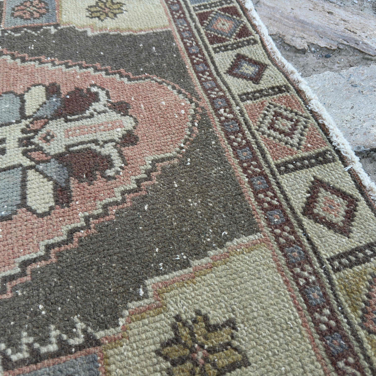 Close-up of the pale red turkish rug showing traditional details, hand-knotted weave, wool and cotton and low pile.