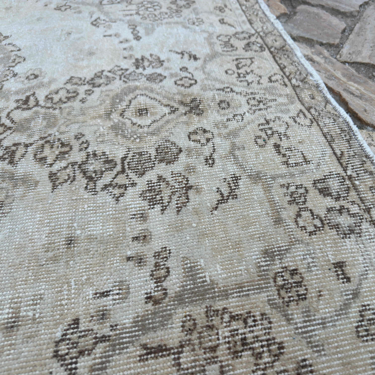 Close-up of the beige turkish rug showing neutral details, hand-knotted weave, wool and cotton and low pile.