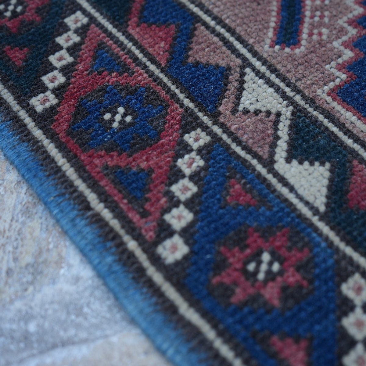 Red 2' x 9' turkish runner rug in wool, shown on the floor.