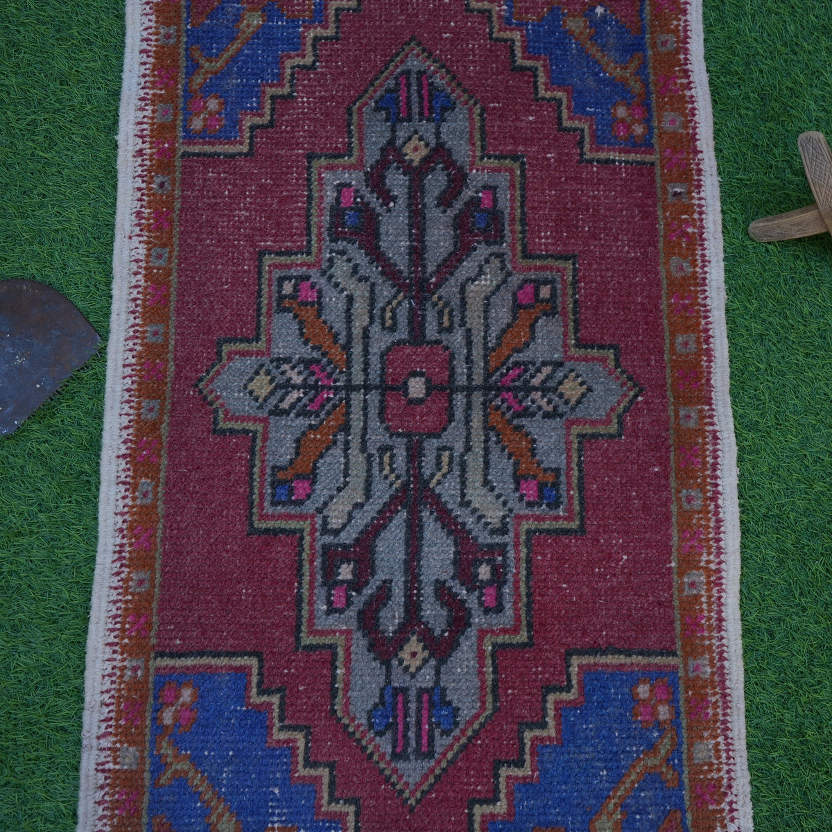 Close-up of the red turkish small rug showing geometric details, hand-knotted weave, wool and cotton and low pile.
