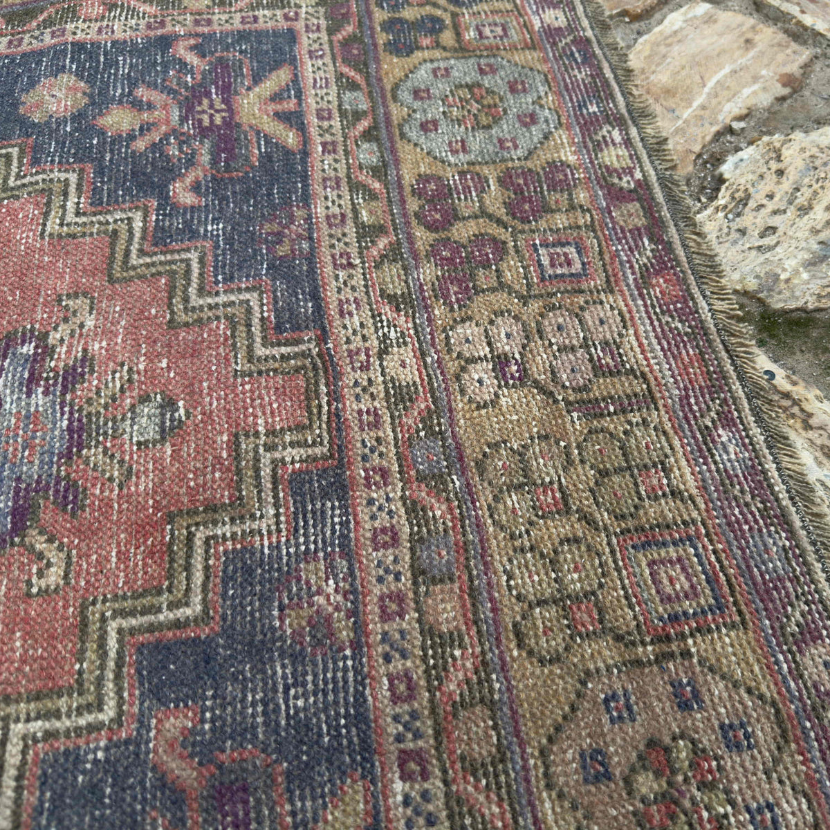 Close-up of the red vintage Turkish anatolian rug showing traditional details, hand-knotted weave, wool and cotton and low pile.