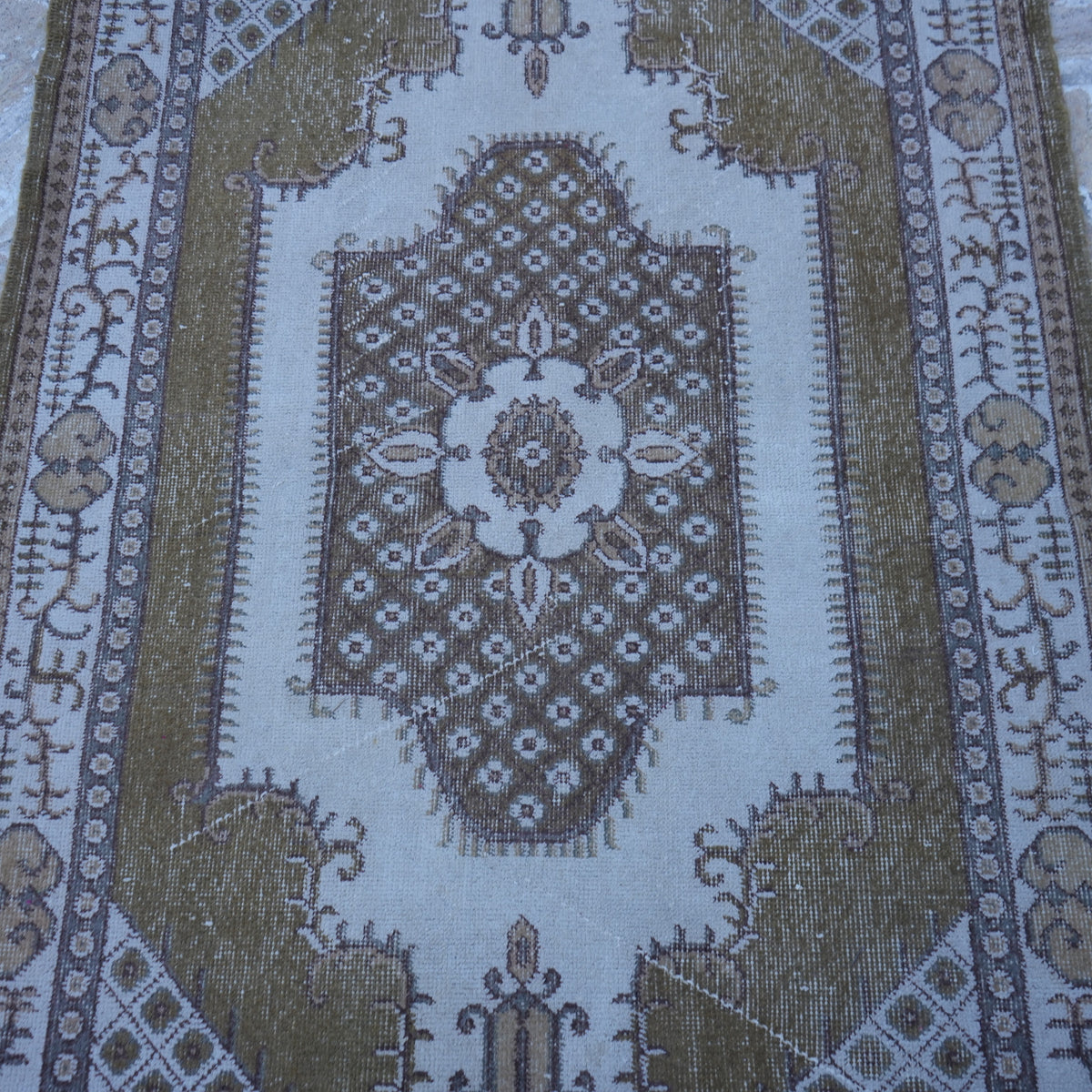 Close-up of the olive green vintage Turkish anatolian rug showing traditional details, hand-knotted weave, wool and cotton and low pile.