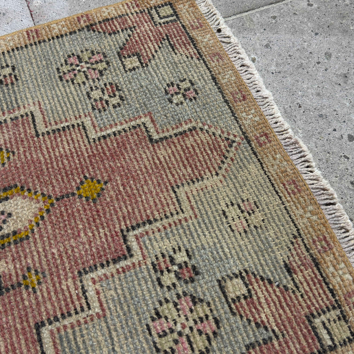 Close-up of the red vintage Turkish area rug showing medallion details, hand-knotted weave, wool and cotton and low pile.