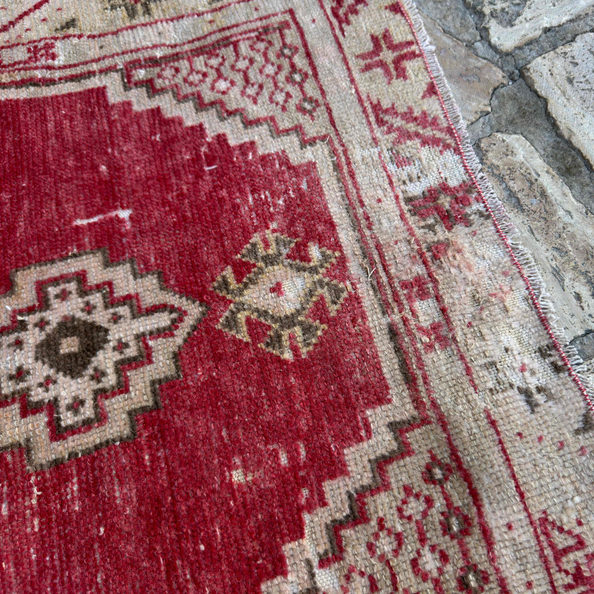 Close-up of the red vintage Turkish area rug showing geometric details, hand-knotted weave, wool and cotton and low pile.