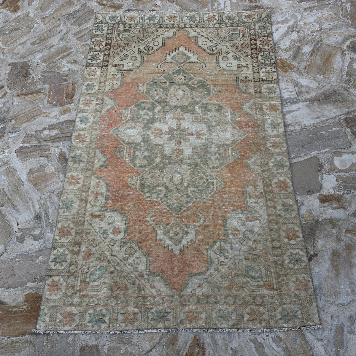 Close-up of the pale orange vintage Turkish area rug showing traditional details, hand-knotted weave, wool and cotton and low pile.