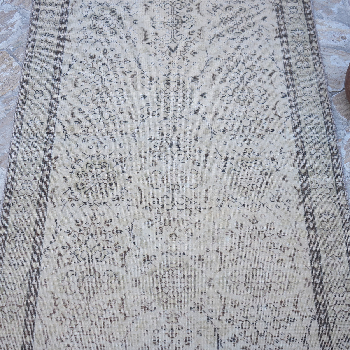 Close-up of the beige vintage Turkish area rug showing traditional details, hand-knotted weave, wool and cotton and low pile.