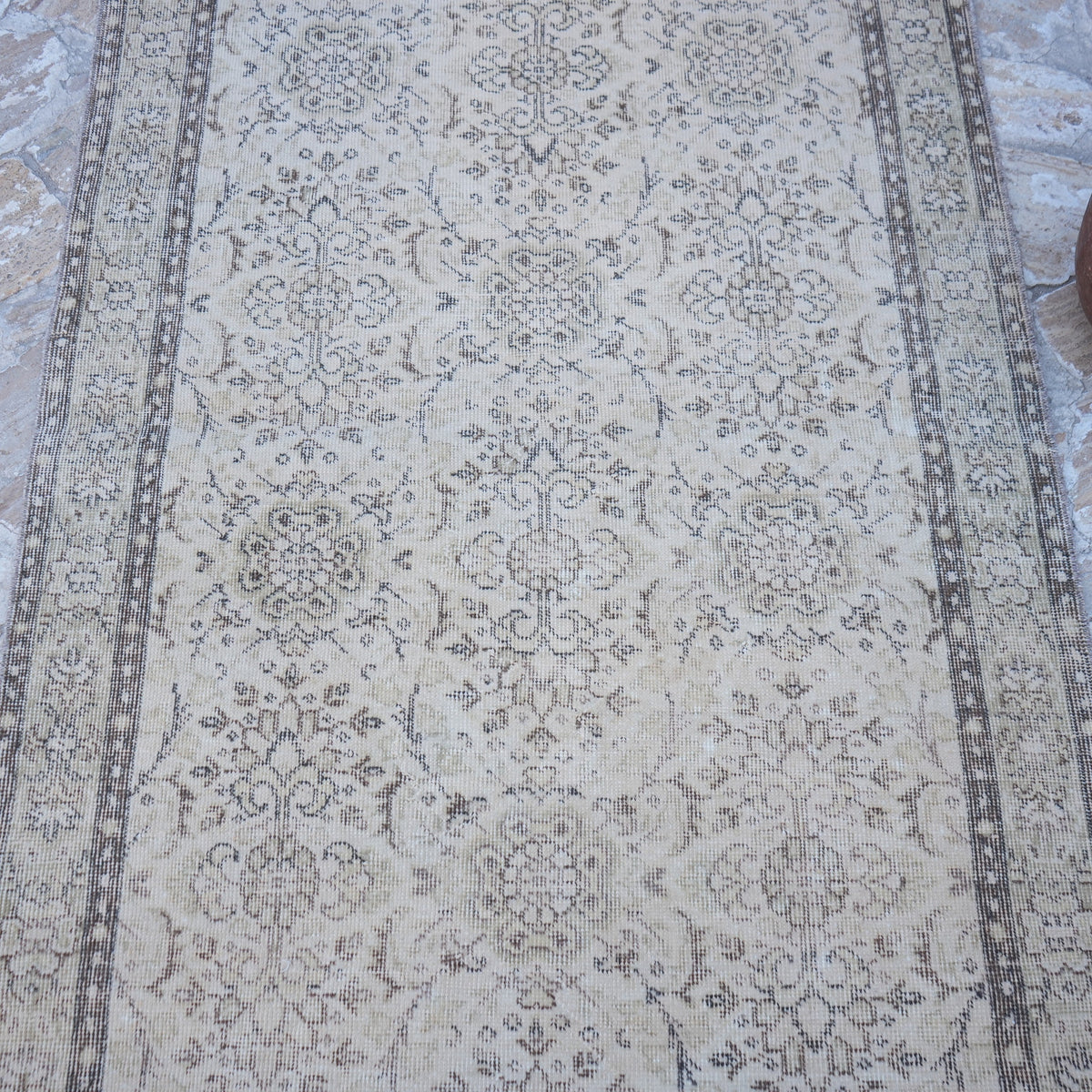 Close-up of the beige vintage Turkish area rug showing traditional details, hand-knotted weave, wool and cotton and low pile.