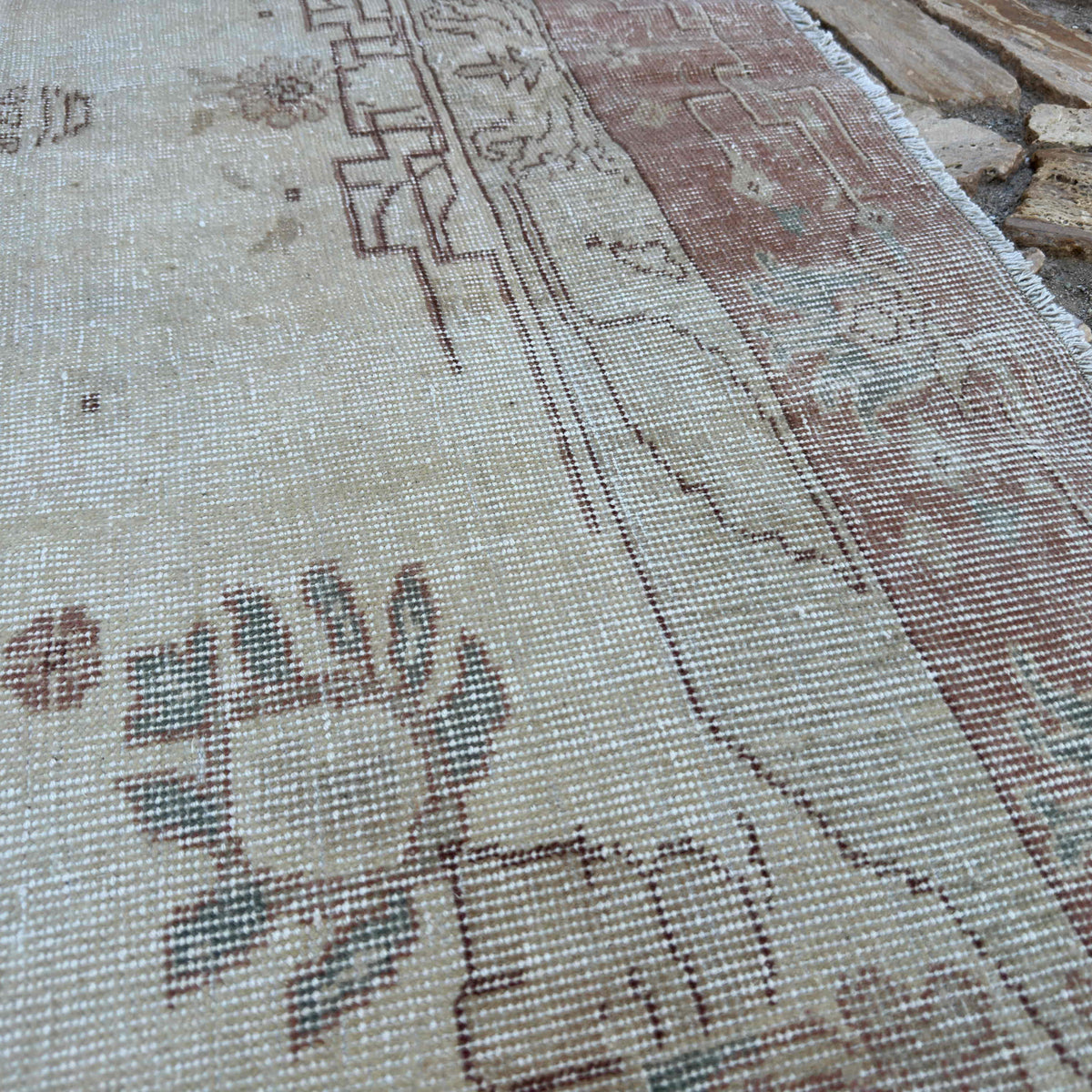 Close-up of the pale red vintage Turkish area rug showing medallion details, hand-knotted weave, wool and cotton and low pile.