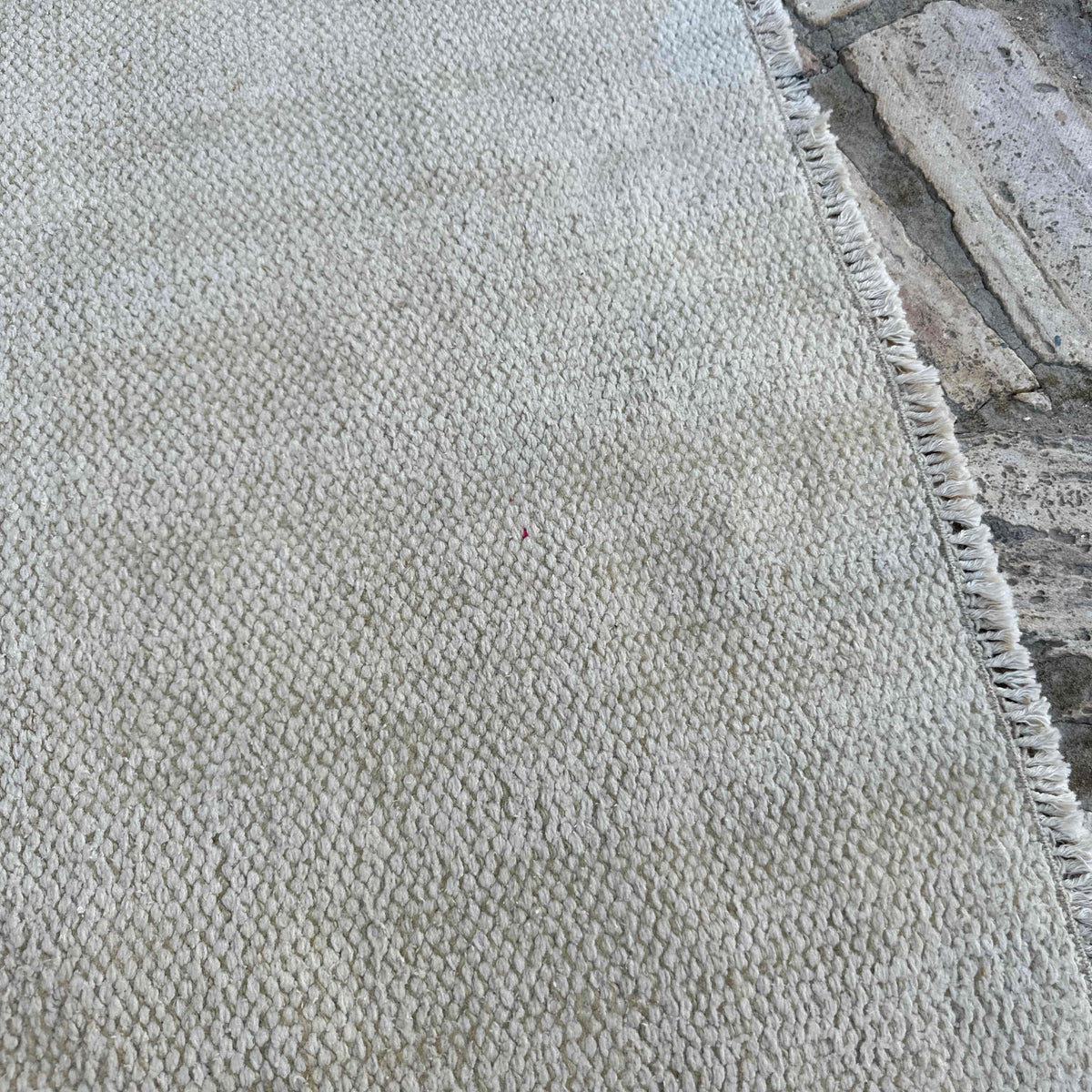 Close-up of the beige vintage Turkish distressed rug showing neutral details, hand-knotted weave, wool and cotton and low pile.