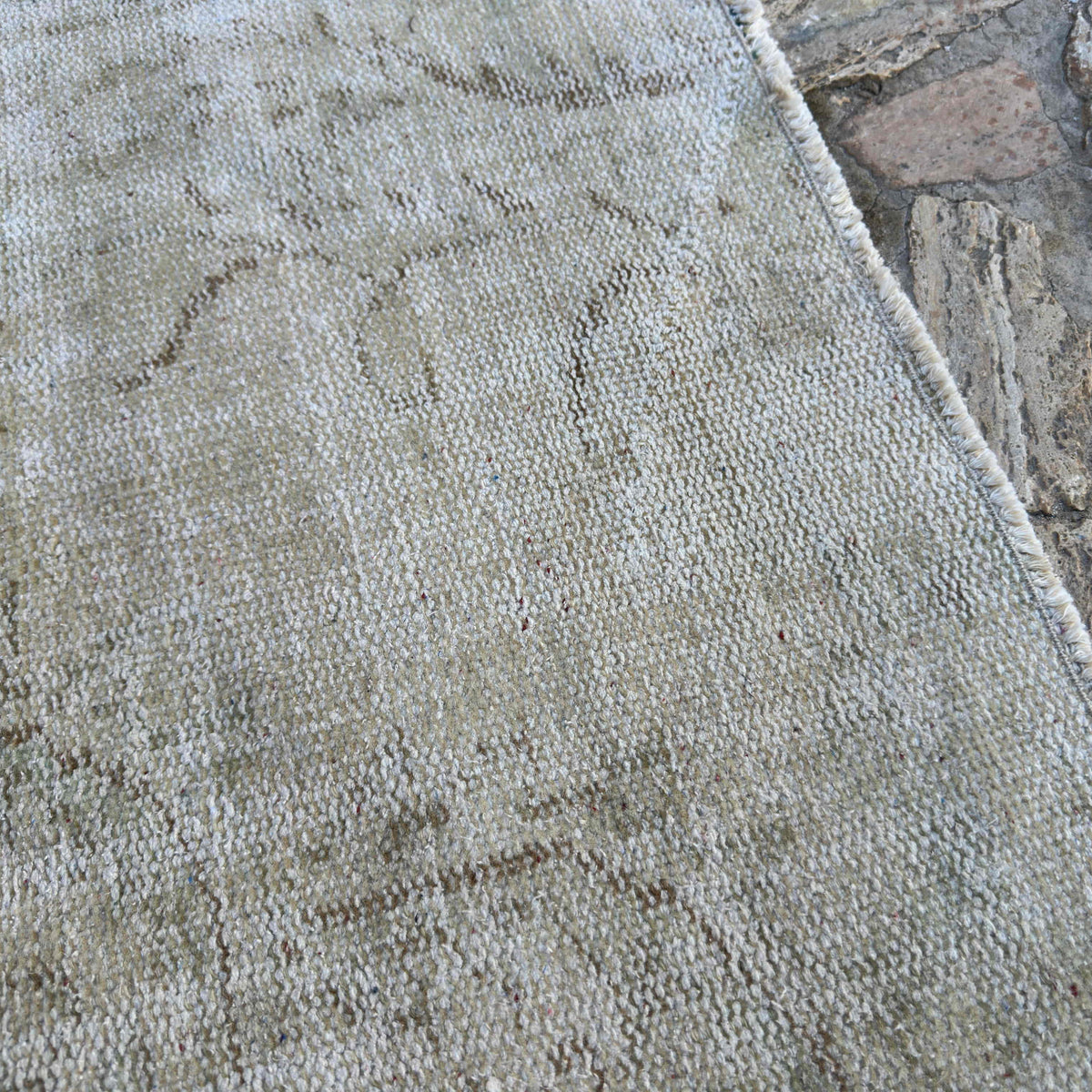 Close-up of the beige vintage Turkish distressed rug showing neutral details, hand-knotted weave, wool and cotton and low pile.