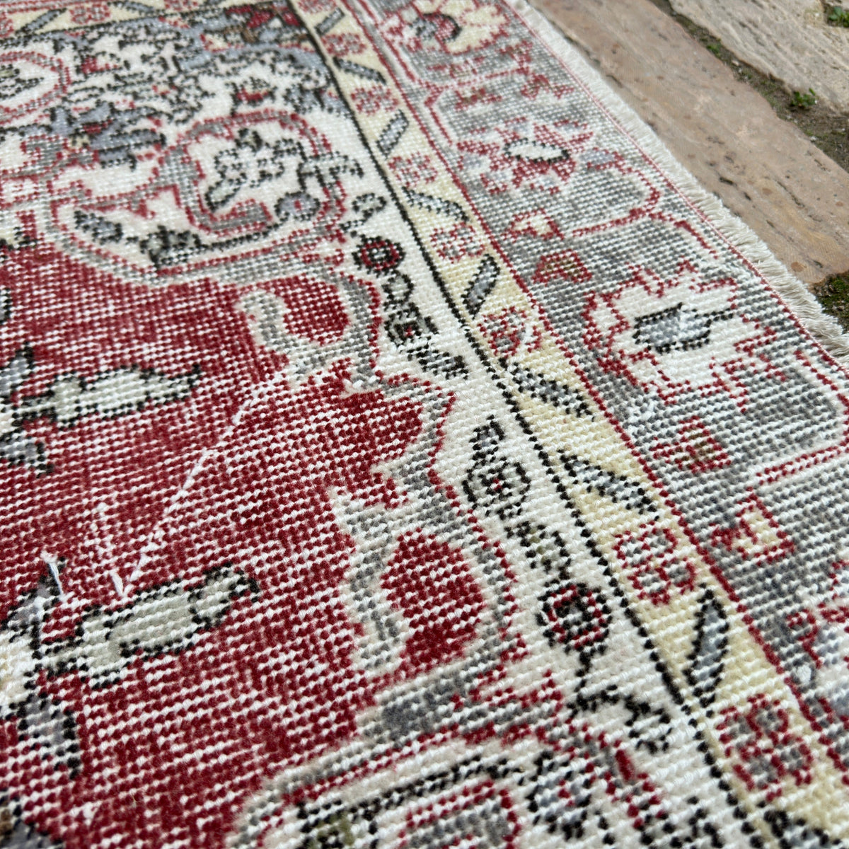 Close-up of the red vintage Turkish distressed rug showing medallion details, hand-knotted weave, wool and cotton and low pile.