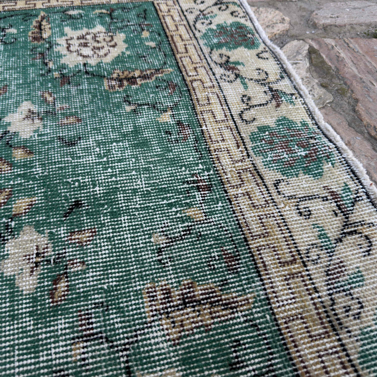 Close-up of the green vintage Turkish distressed rug showing traditional details, hand-knotted weave, wool and cotton and low pile.