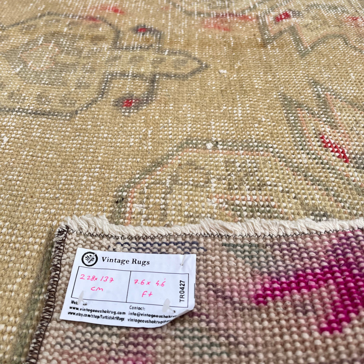 Close-up of the beige vintage Turkish distressed rug showing neutral details, hand-knotted weave, wool and cotton and low pile.