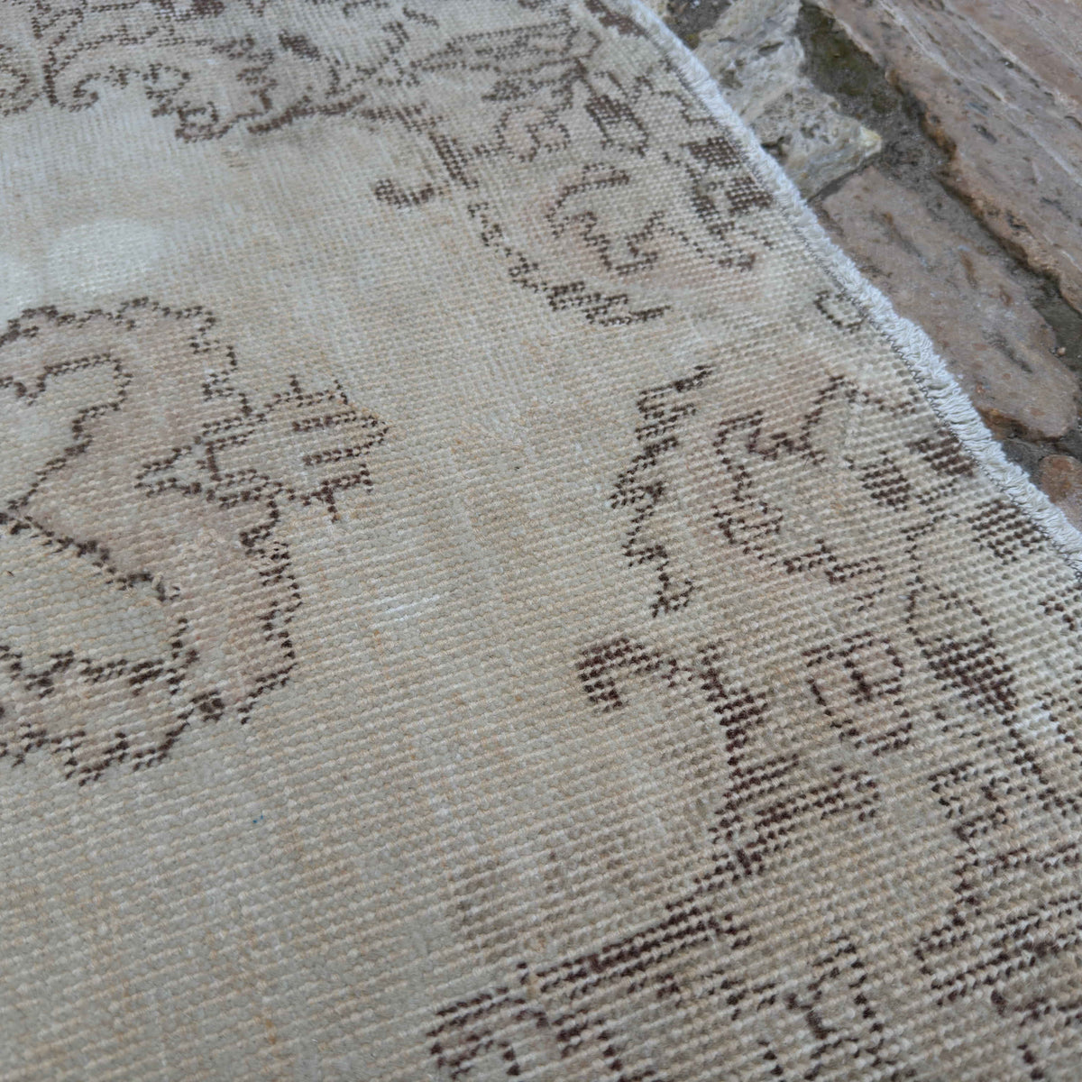 Close-up of the beige vintage Turkish distressed rug showing neutral details, hand-knotted weave, wool and cotton and low pile.