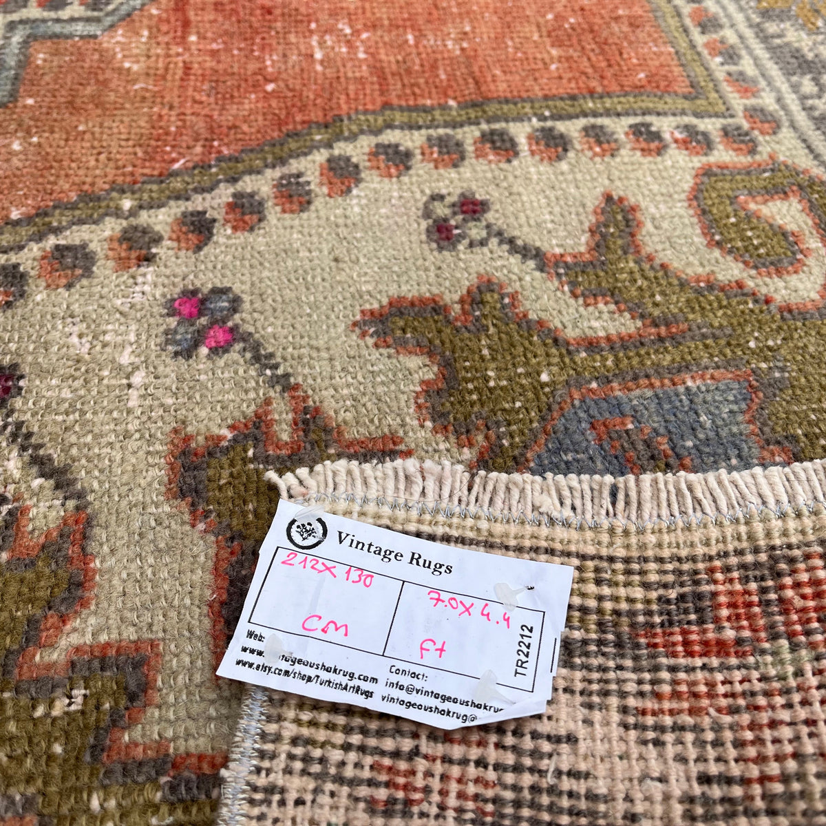 Close-up of the pale red vintage Turkish distressed rug showing traditional details, hand-knotted weave, wool and cotton and low pile.