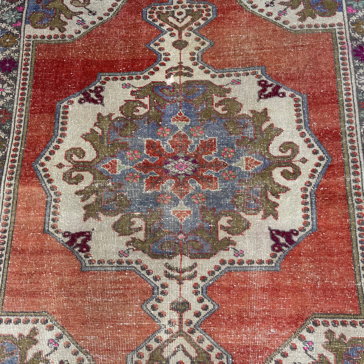 1970s pale red vintage Turkish distressed rug with traditional design, hand-knotted weave and low pile.