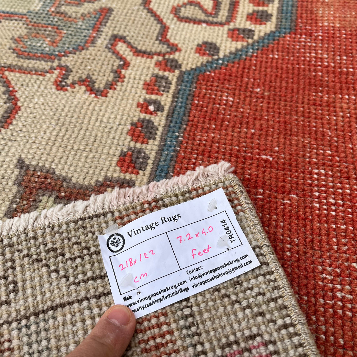 Close-up of the red vintage Turkish distressed rug showing geometric details, hand-knotted weave, wool and cotton and low pile.