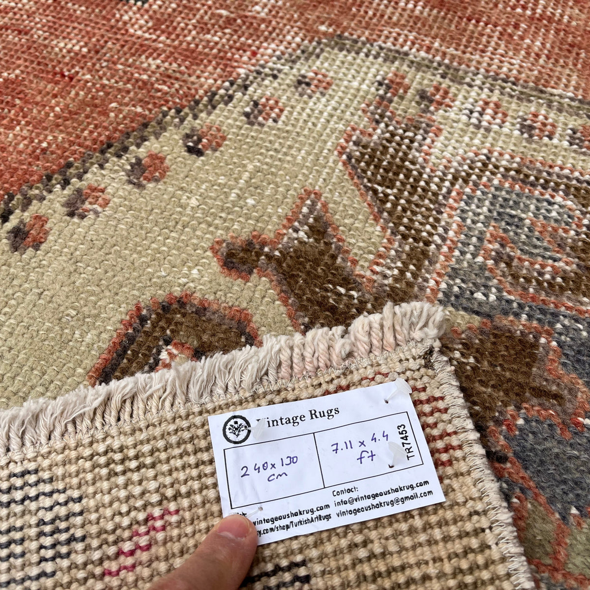 Close-up of the orange vintage Turkish distressed rug showing traditional details, hand-knotted weave, wool and cotton and low pile.