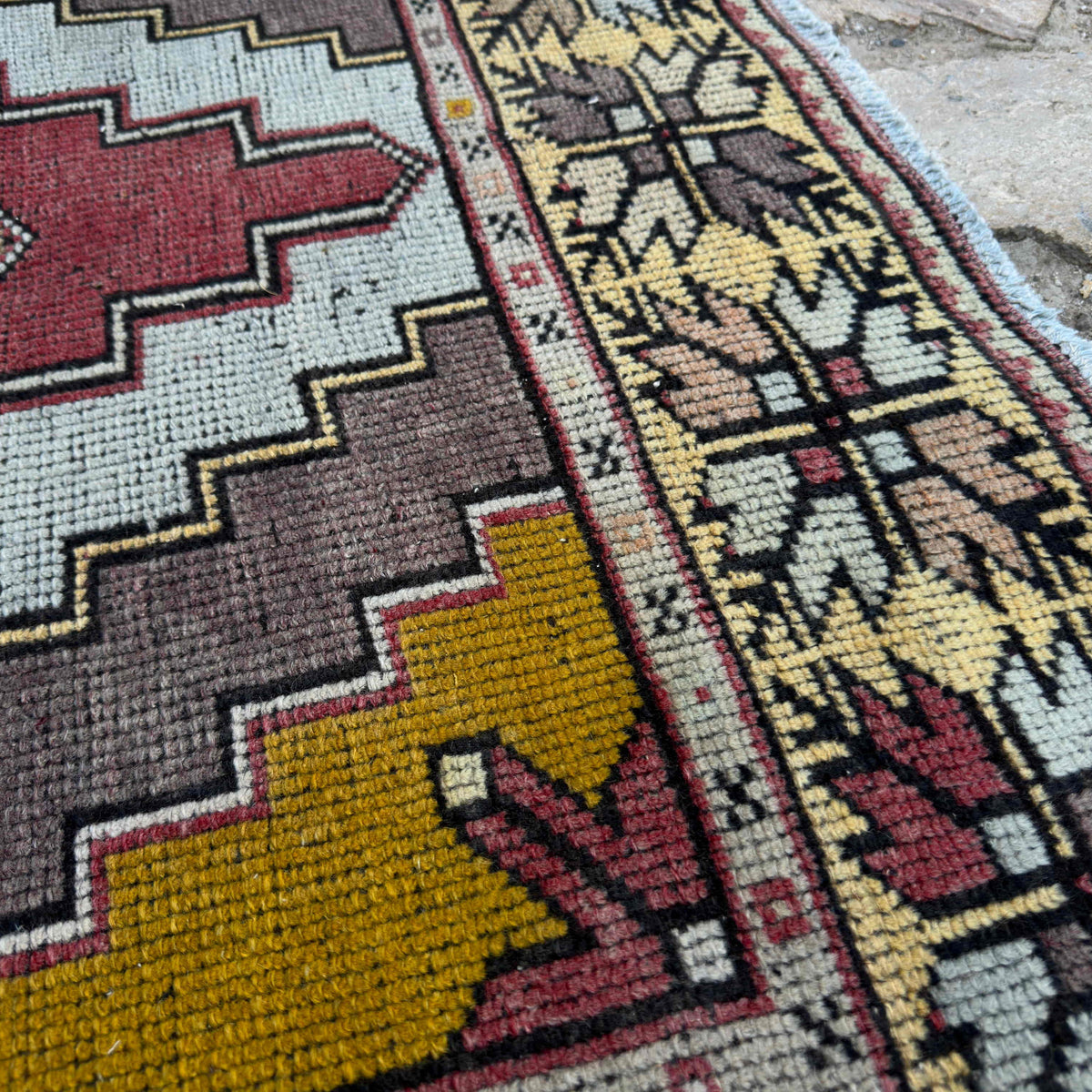 Close-up of the red vintage Turkish distressed rug showing traditional details, hand-knotted weave, wool and cotton and low pile.