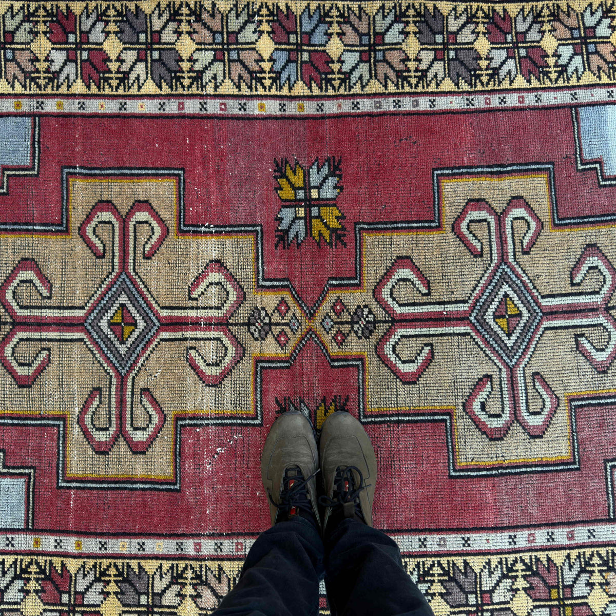 1970s red vintage Turkish distressed rug with traditional design, hand-knotted weave and low pile.