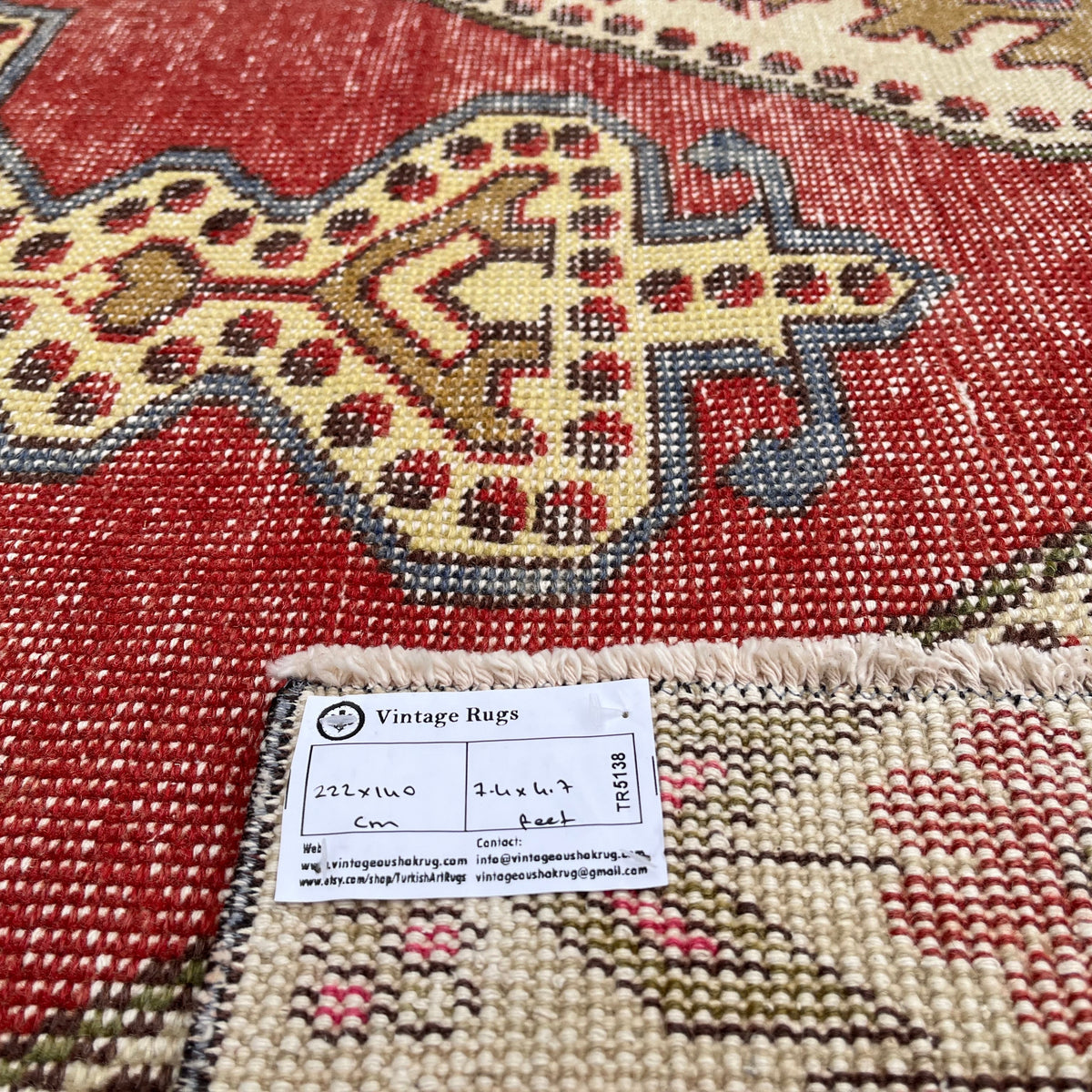 Close-up of the red vintage Turkish distressed rug showing traditional details, hand-knotted weave, wool and cotton and low pile.
