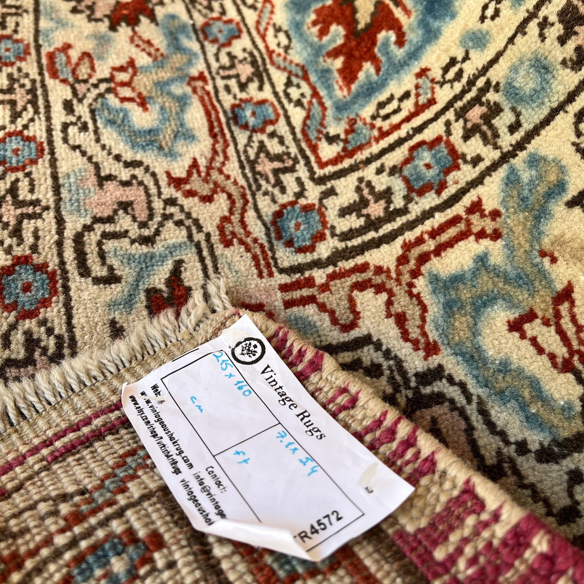 Close-up of the red vintage Turkish distressed rug showing medallion details, hand-knotted weave, wool and cotton and low pile.