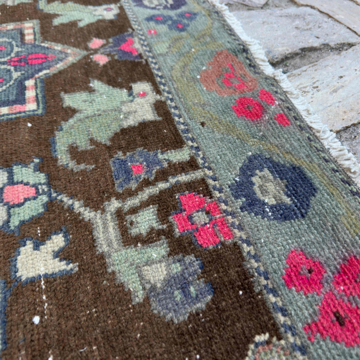 Close-up of the brown vintage Turkish distressed rug showing geometric details, hand-knotted weave, wool and cotton and low pile.