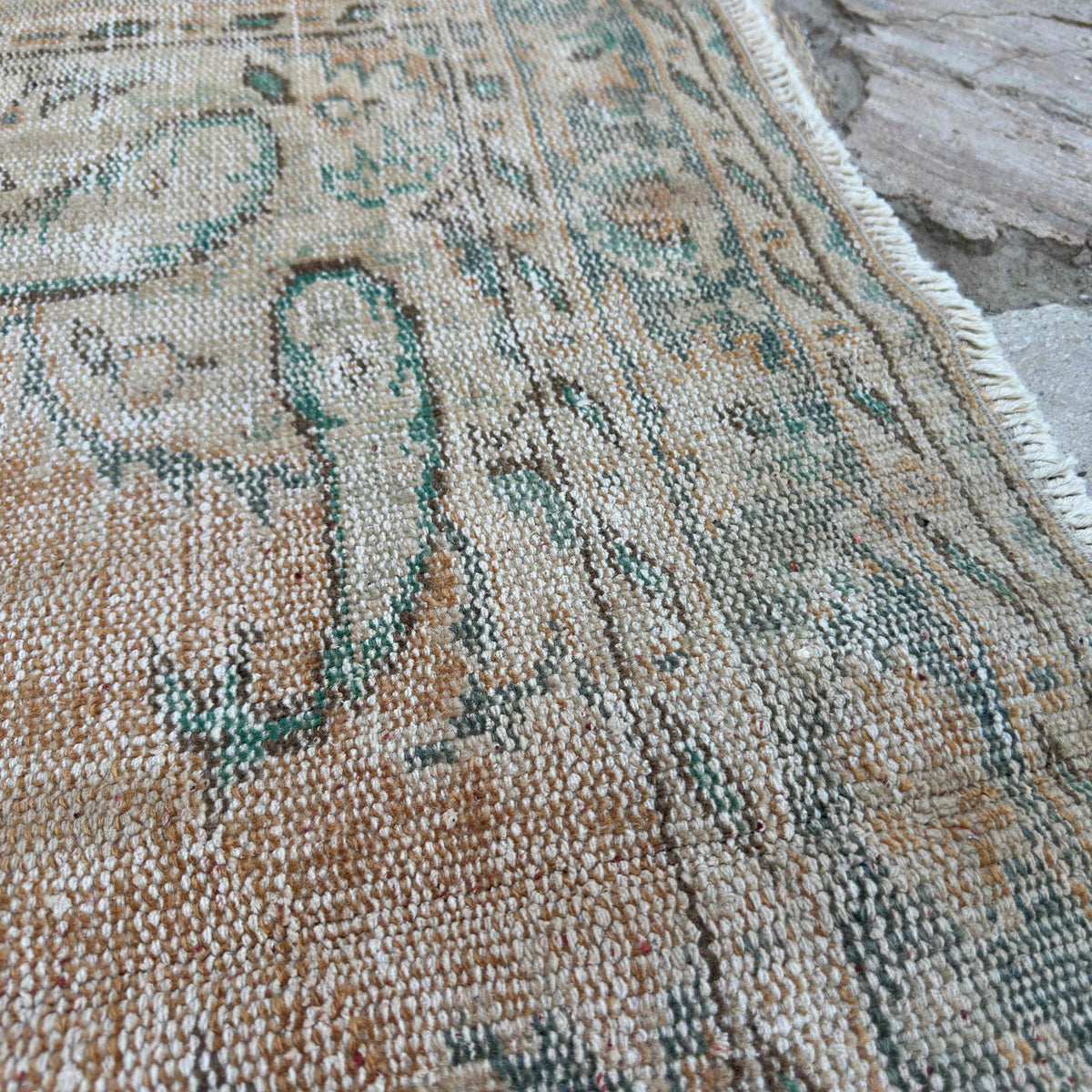 Close-up of the orange vintage Turkish distressed rug showing medallion details, hand-knotted weave, wool and cotton and low pile.