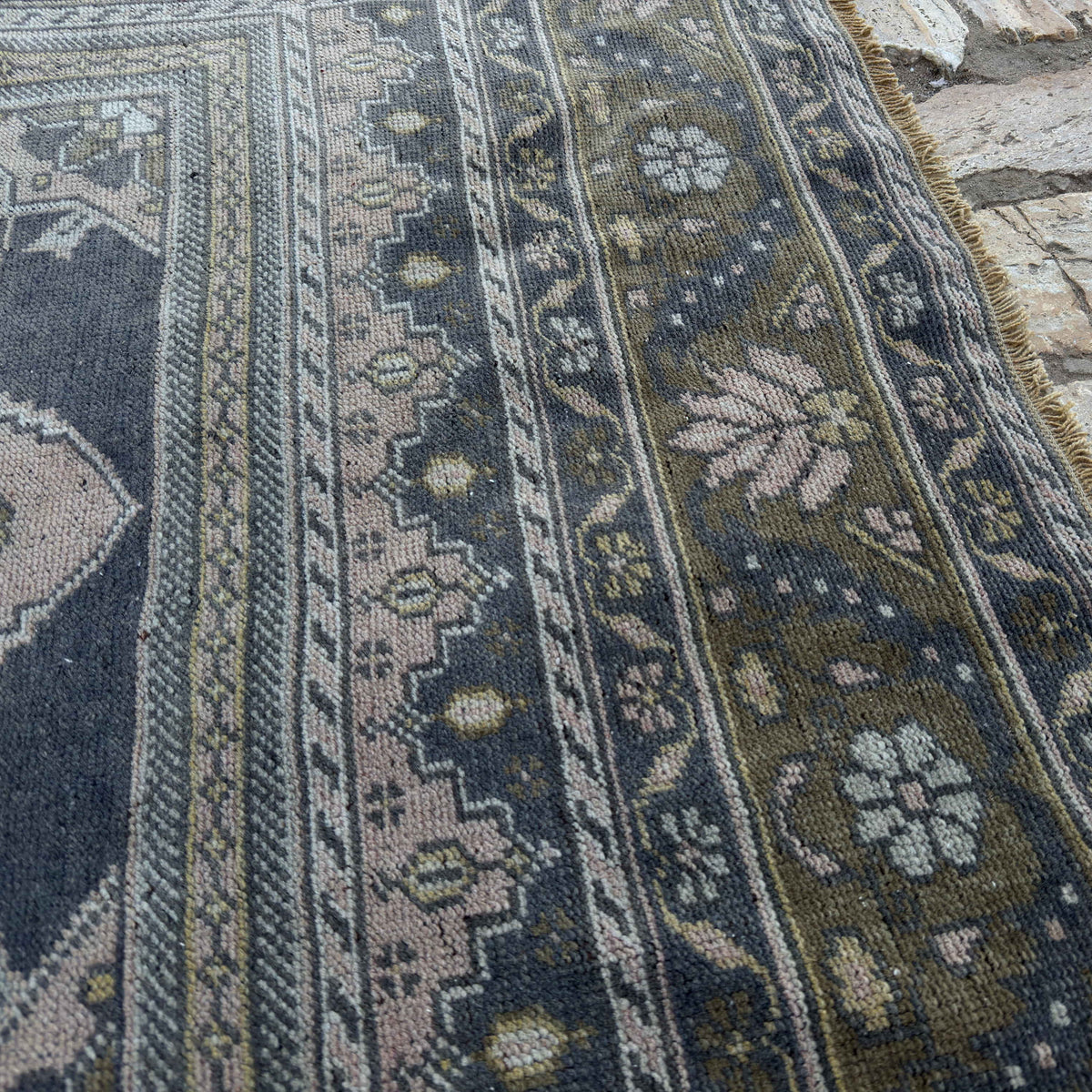 Close-up of the pink vintage Turkish distressed rug showing traditional details, hand-knotted weave, wool and cotton and low pile.