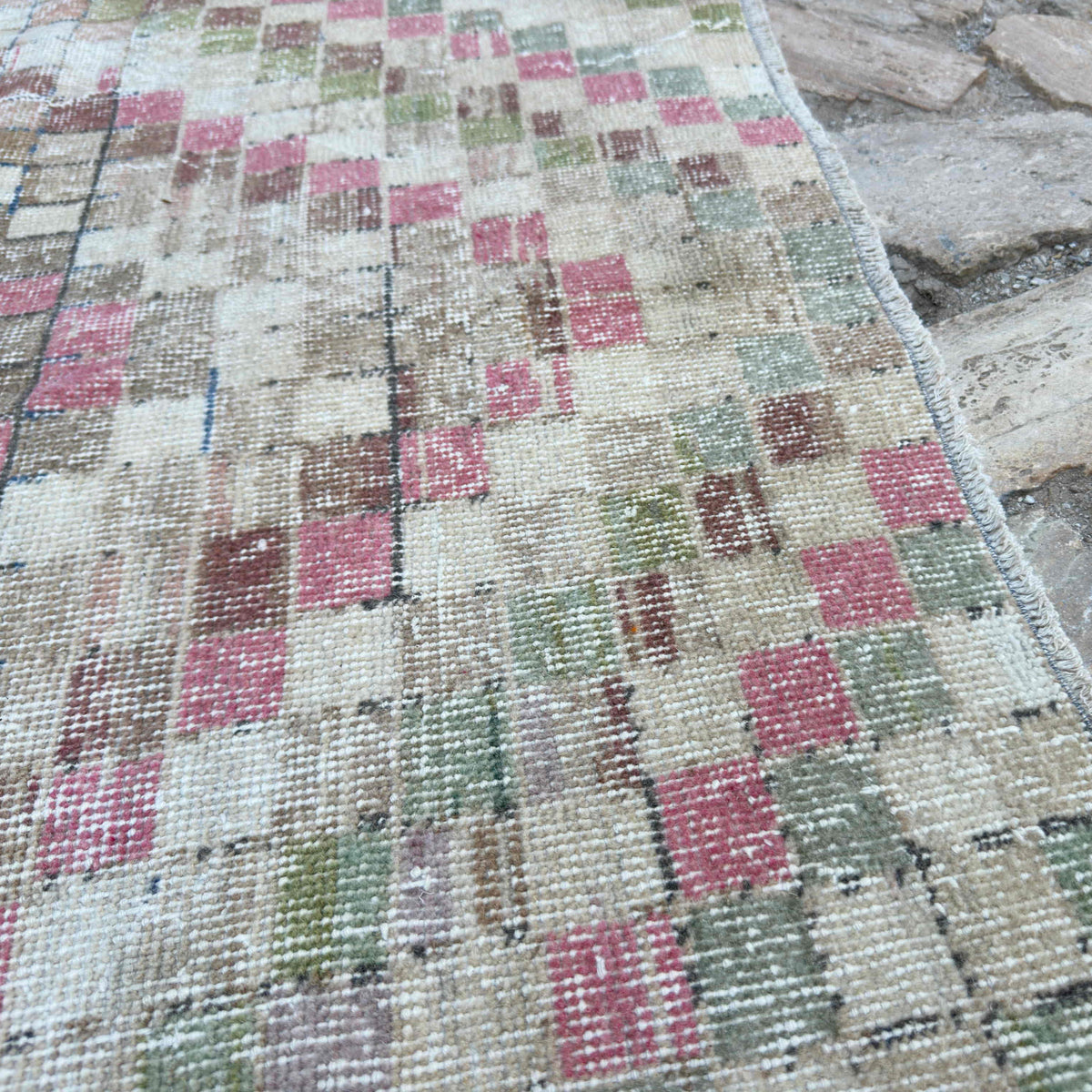 Close-up of the pink vintage Turkish distressed rug showing traditional details, hand-knotted weave, wool and cotton and low pile.